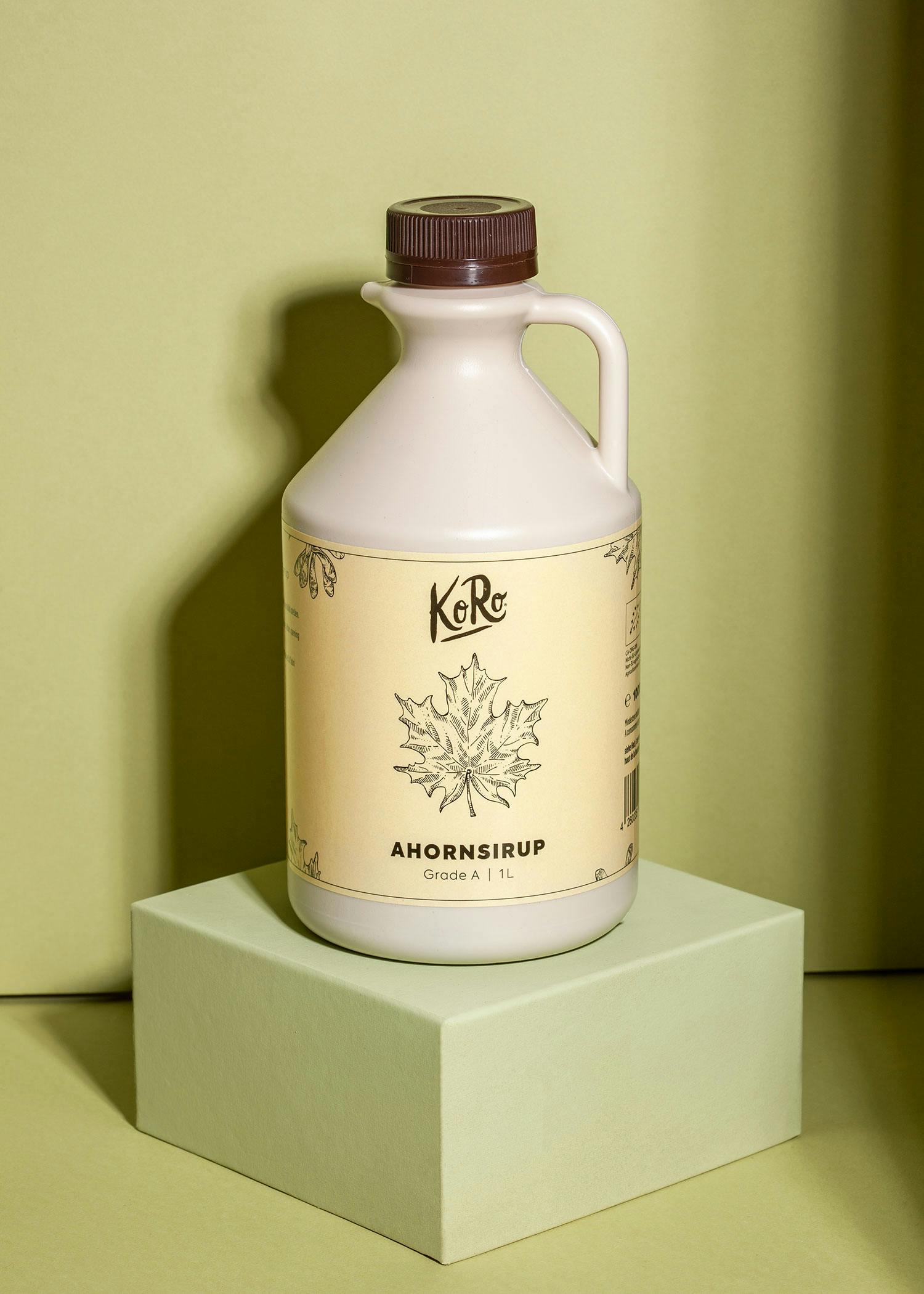 eine Flasche ahornsirup steht auf einem grünen würfel