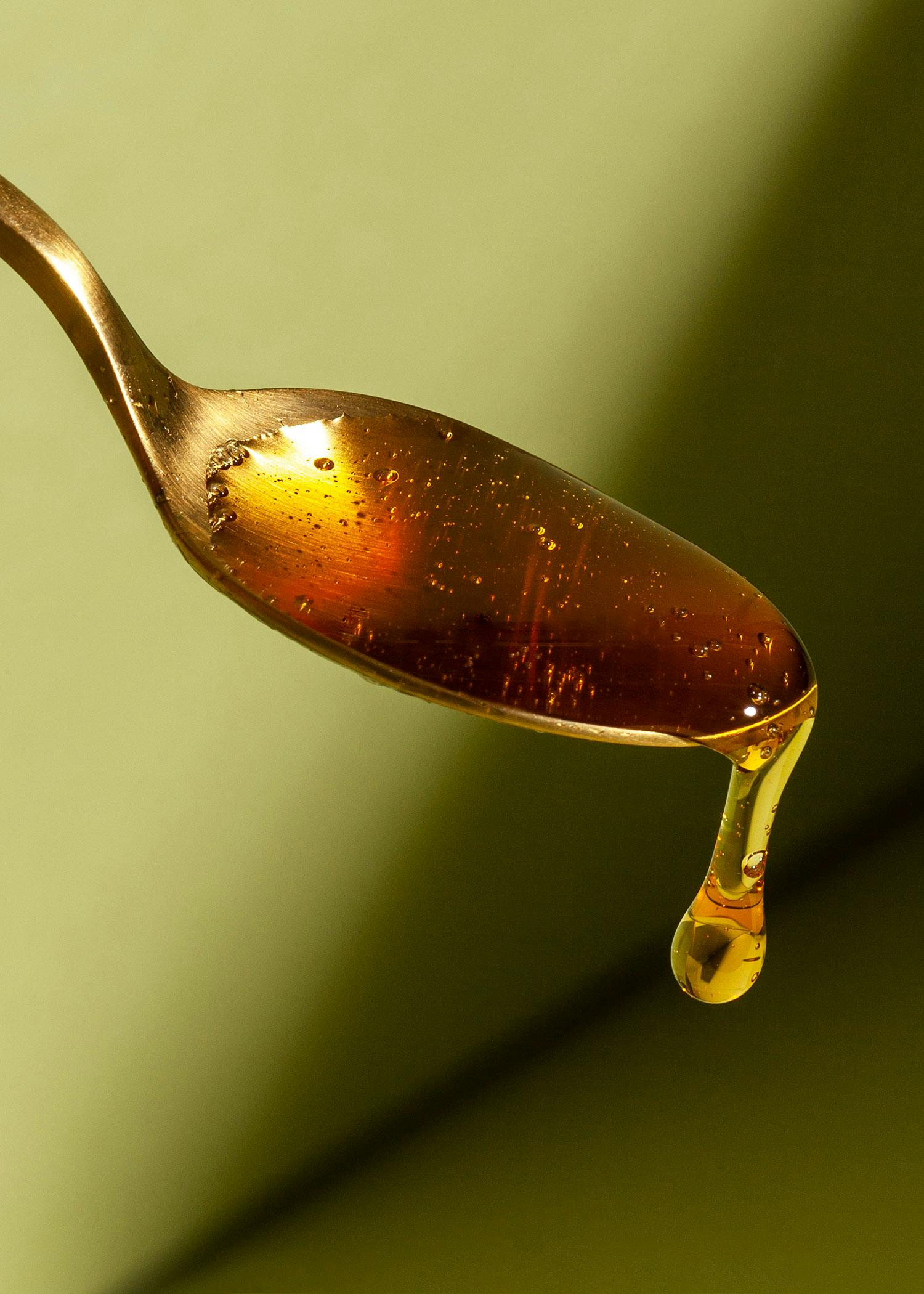 ein goldener Löffel mit einem Tropfen Honig darauf