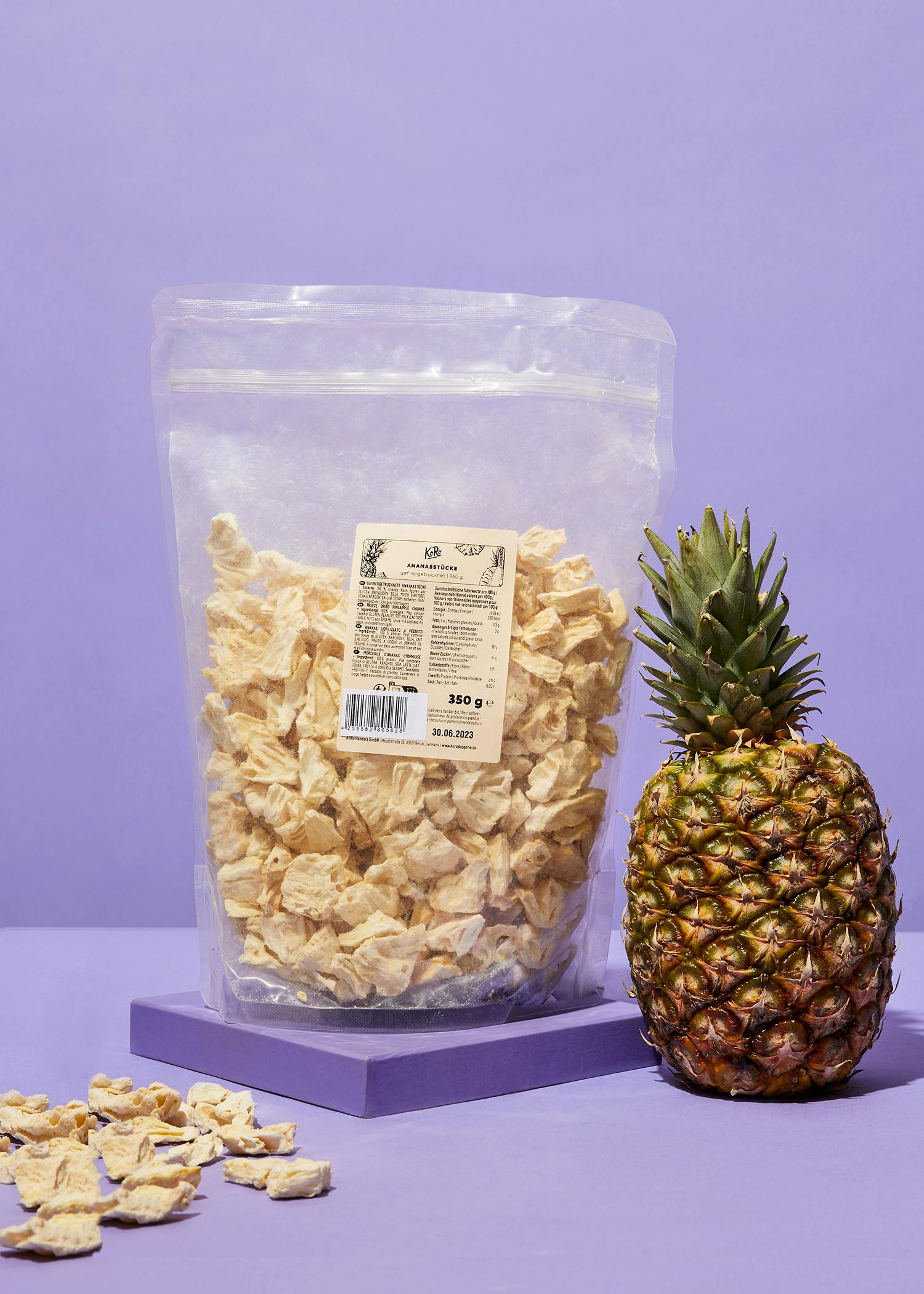 eine große Tüte getrocknete Bananen steht neben einer Ananas