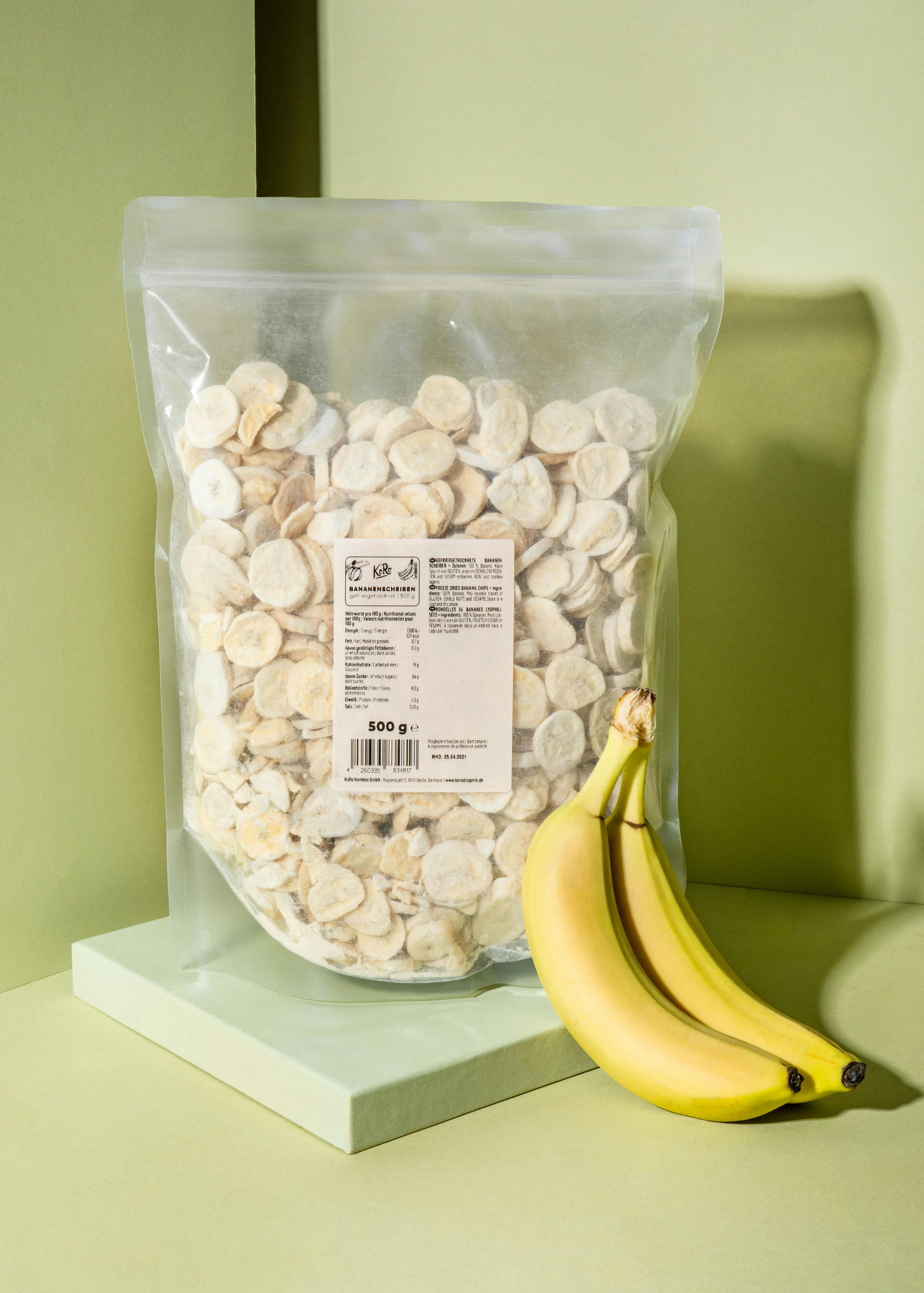 eine Banane sitzt neben einem Plastikbeutel mit Bananenchips