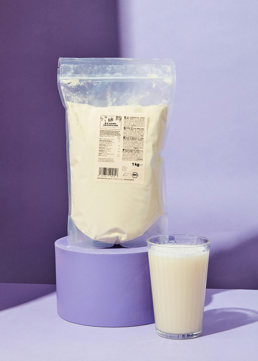 ein Glas Milch steht neben einer Tüte Milchpulver