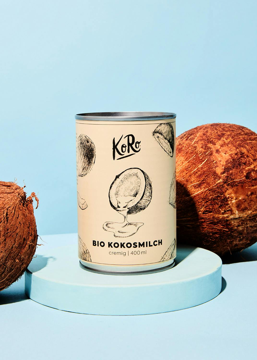 eine Dose Kokosmilch steht neben Kokosnüssen