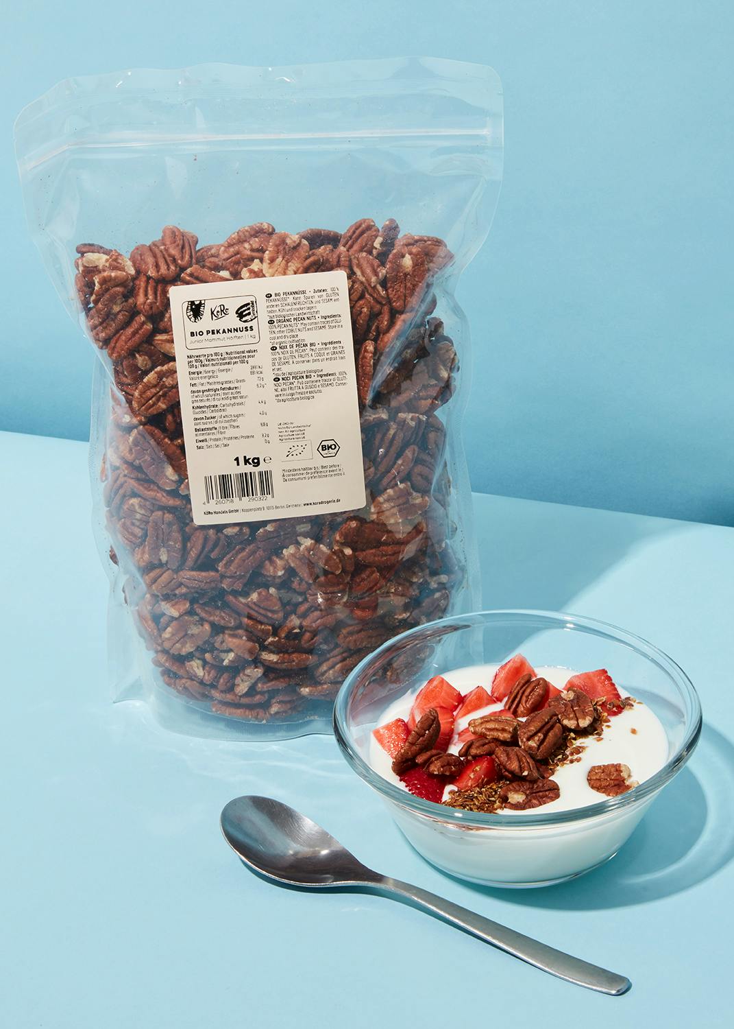 eine Tüte Pekannüsse steht neben einer Schüssel Joghurt mit Erdbeeren