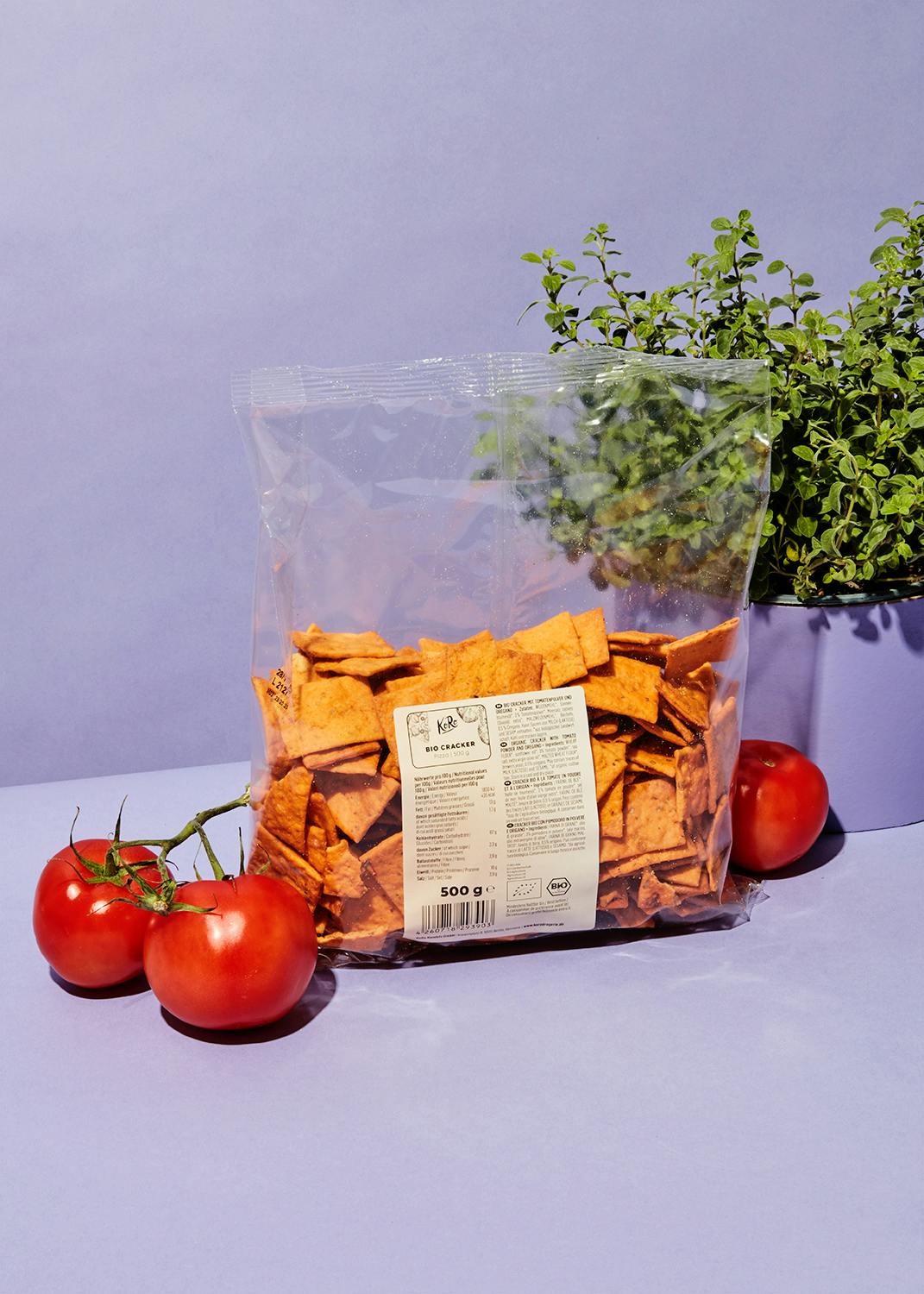 eine Tüte Chips steht neben Tomaten und Kräutern