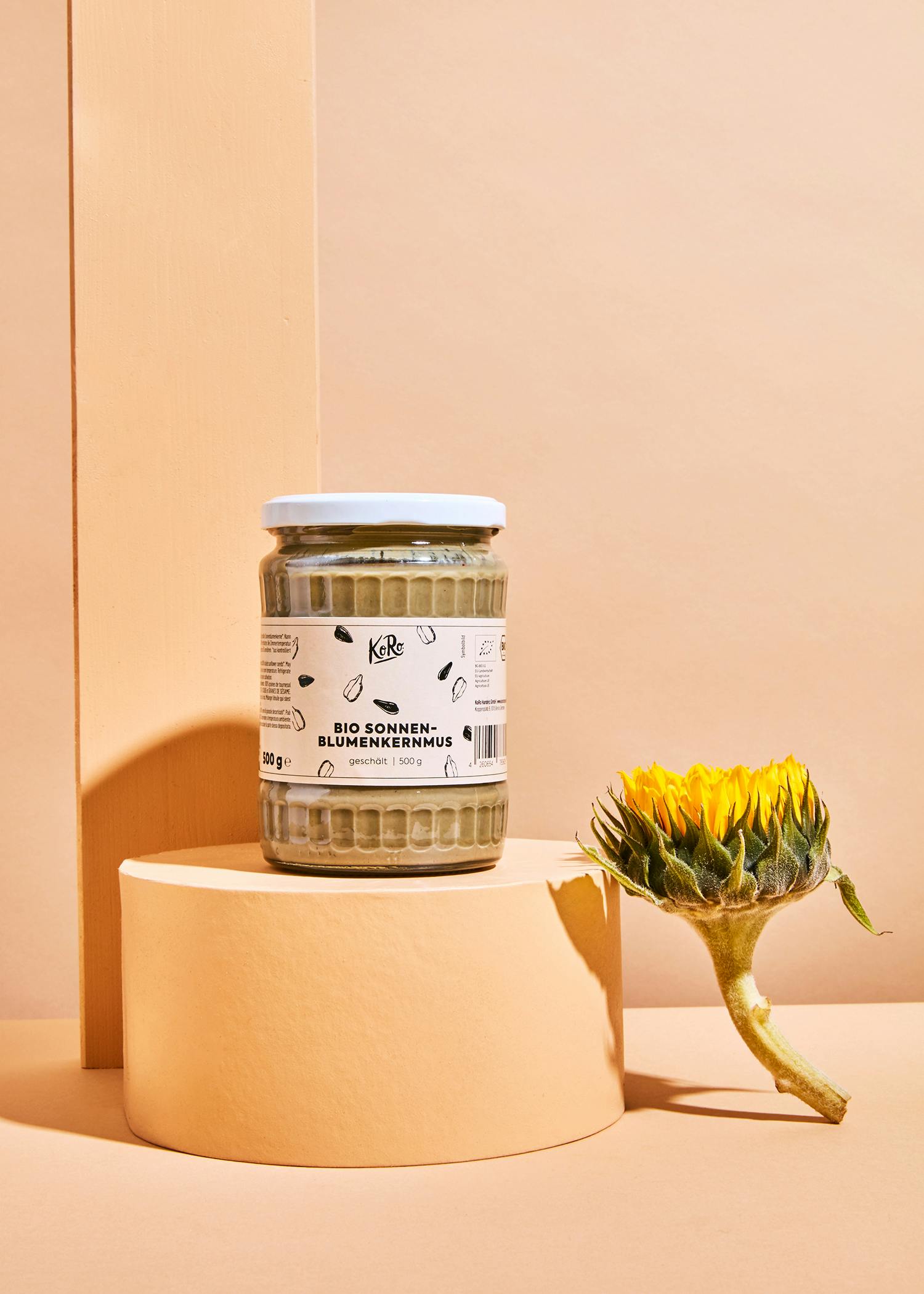 ein Glas Sonnenblumenkernmus steht neben einer Sonnenblume