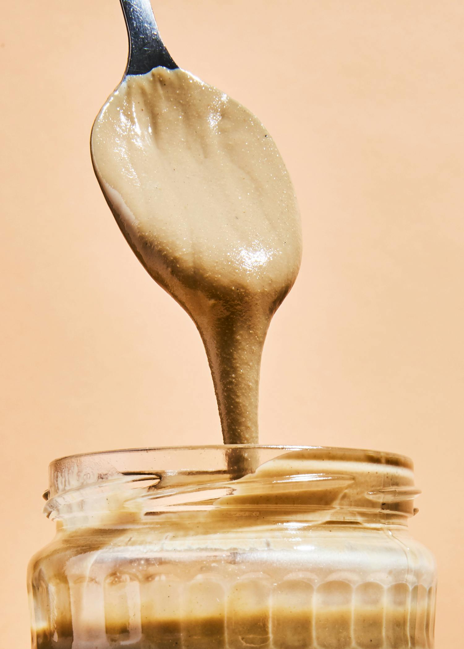 Ein Löffel Erdnussbutter wird in ein Glas gegossen