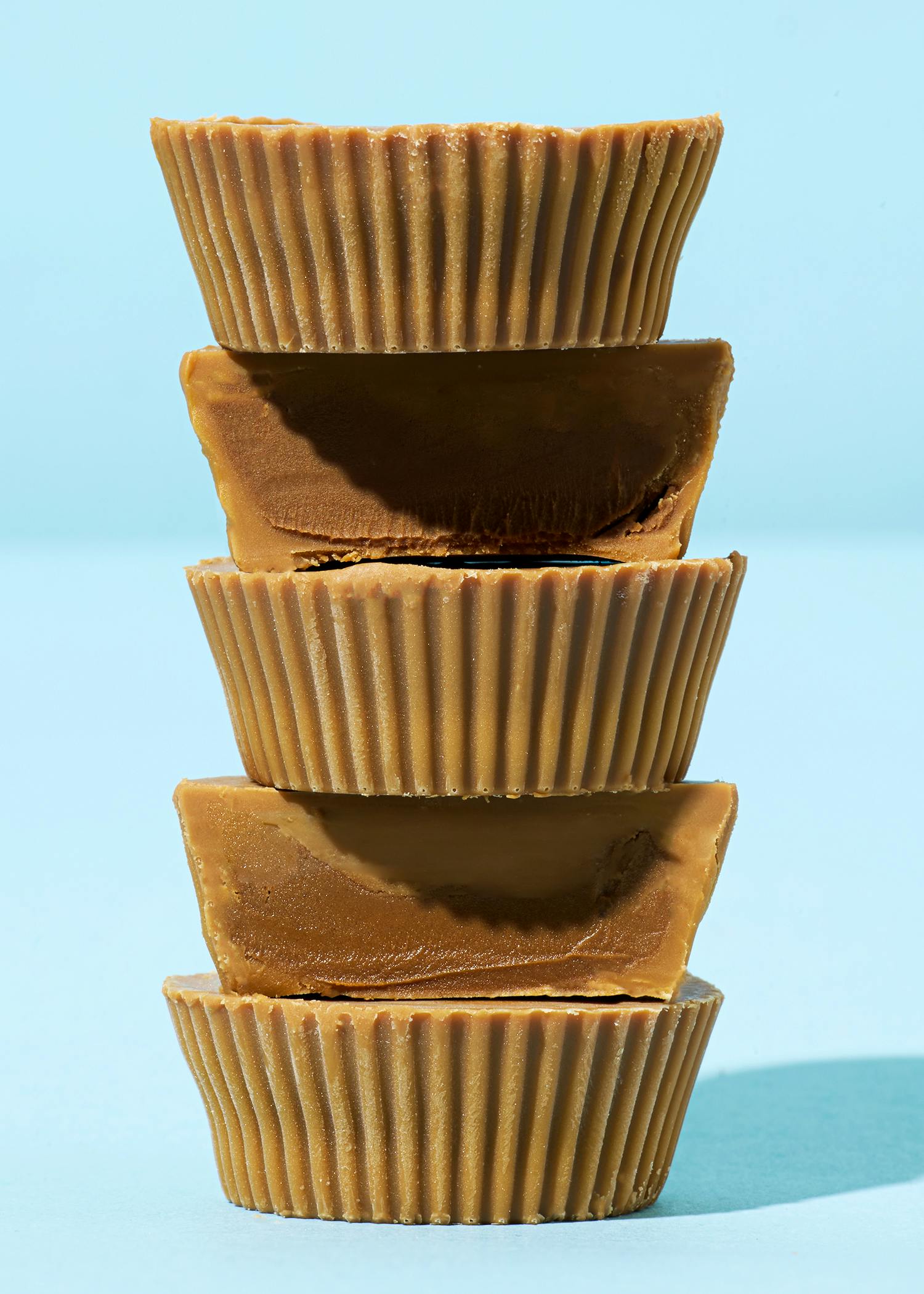 vier Erdnussbuttercups stapeln sich aufeinander auf einem blauen Hintergrund