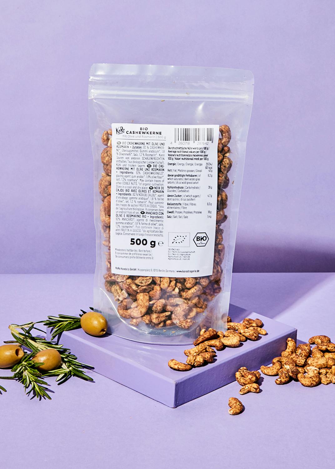 eine Plastiktüte mit gerösteten Cashewnüssen steht auf einem lila Tisch