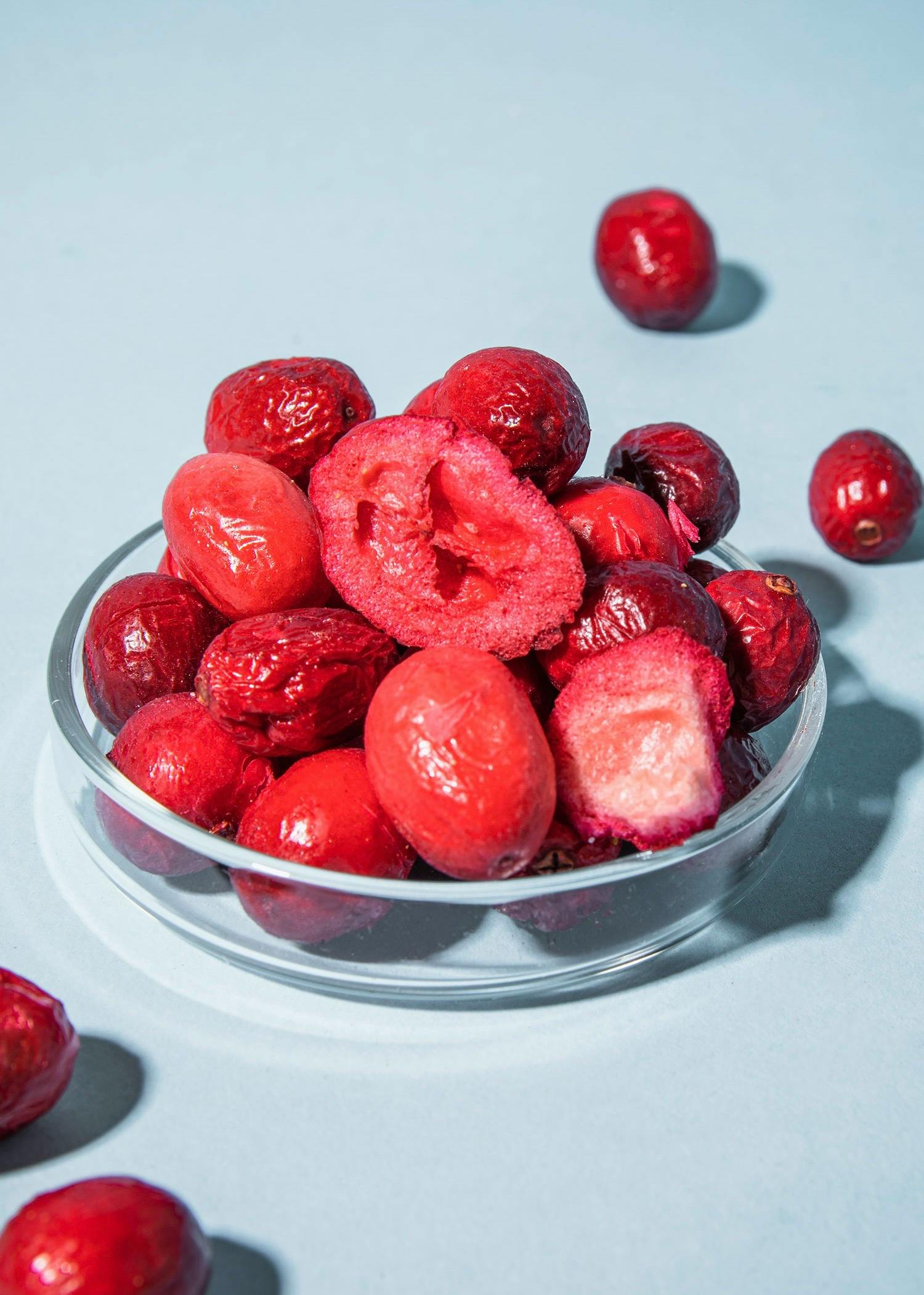 eine Glasschale mit roten Beeren auf einem Tisch