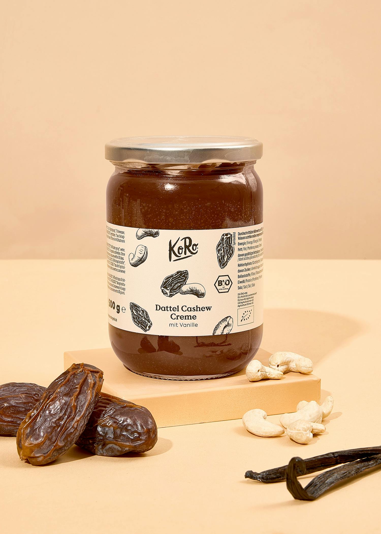 ein Glas mit einem Deckel und einem weißen Aufkleber steht auf einem Tisch neben datteln und cashewkernen