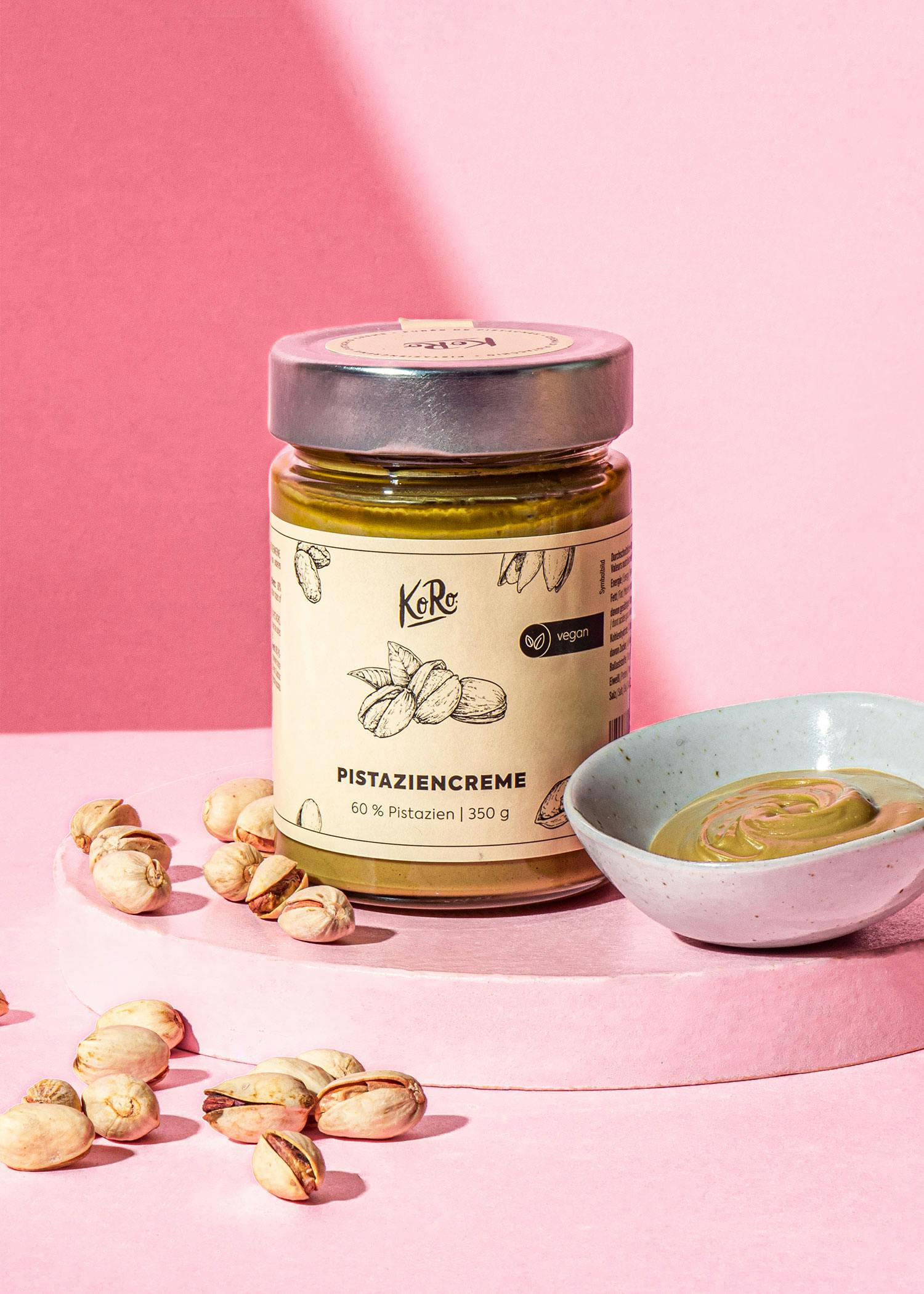 eine Flasche pistaziencreme steht auf einem rosa Tisch