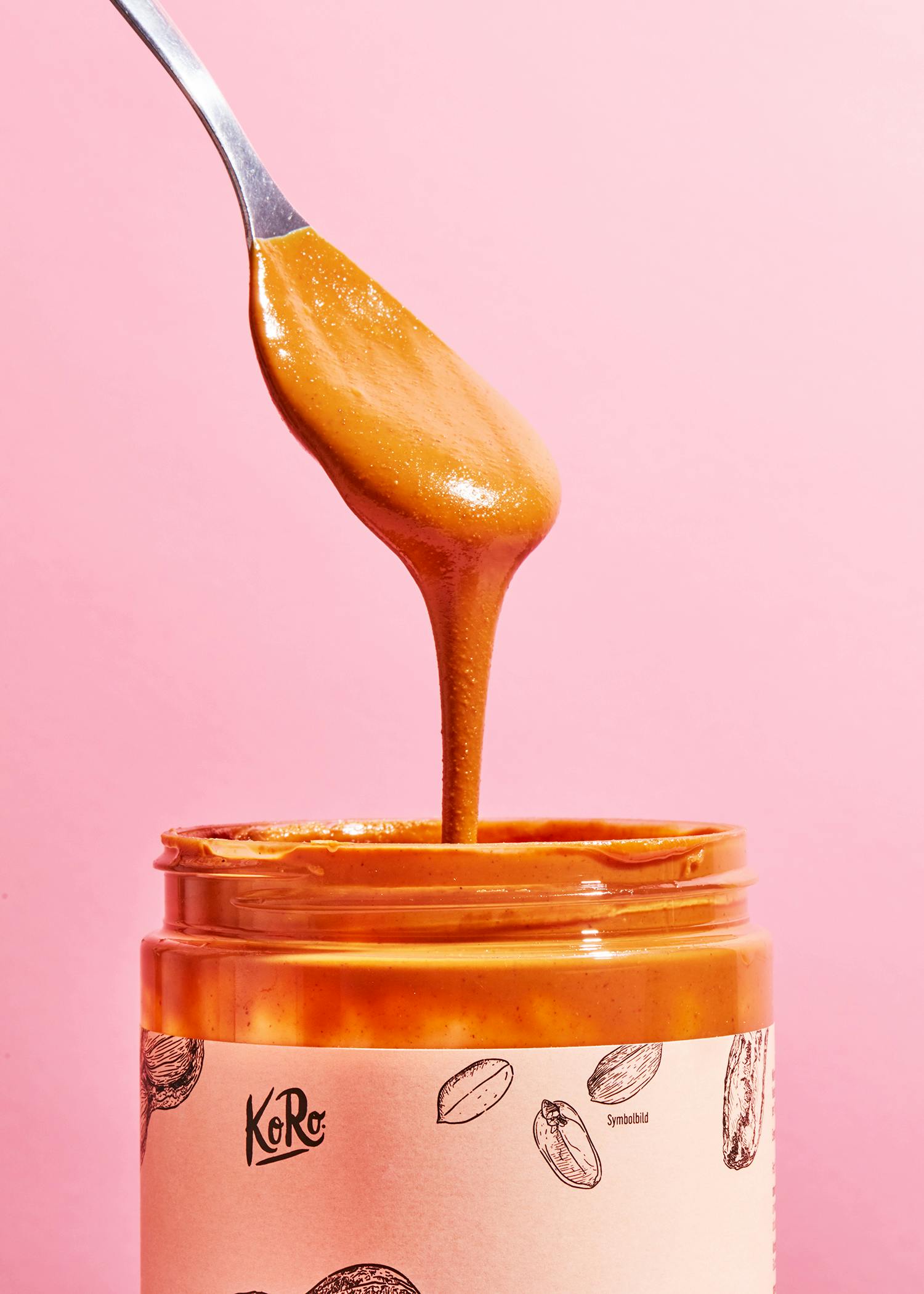 ein Löffel Erdnussbutter kommt aus einer Karamellmarmelade-Flasche