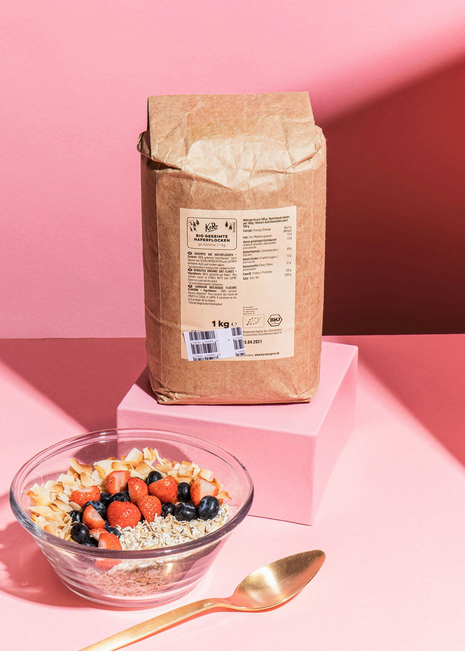 ein brauner Karton steht neben einer Glasschüssel mit Müsli und einem Löffel