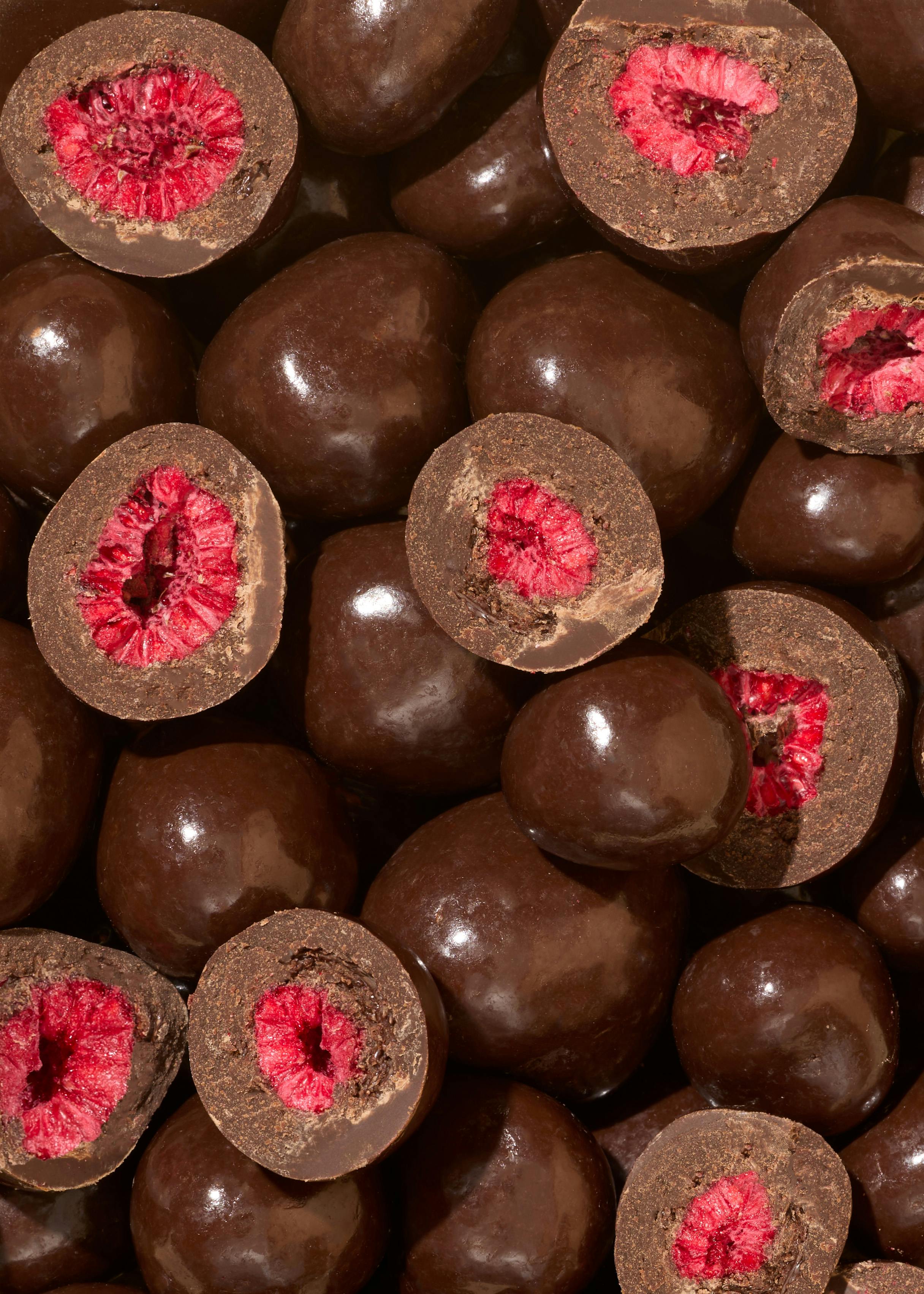 ein Haufen Schokoladenüberzogener Himbeeren mit einem Loch in der Mitte