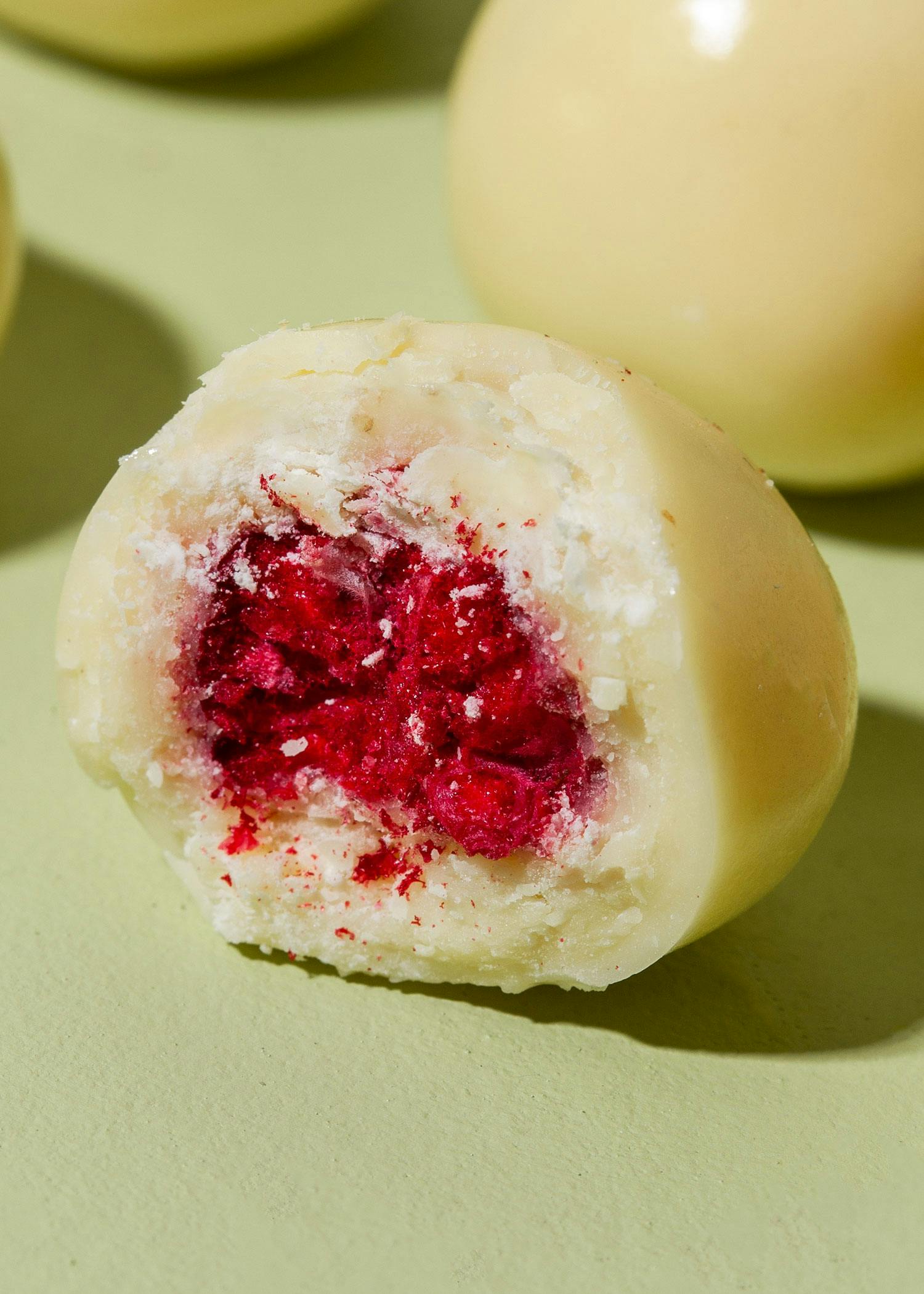 eine Nahaufnahme einer weißen Schokolade mit einer roten Frucht darin