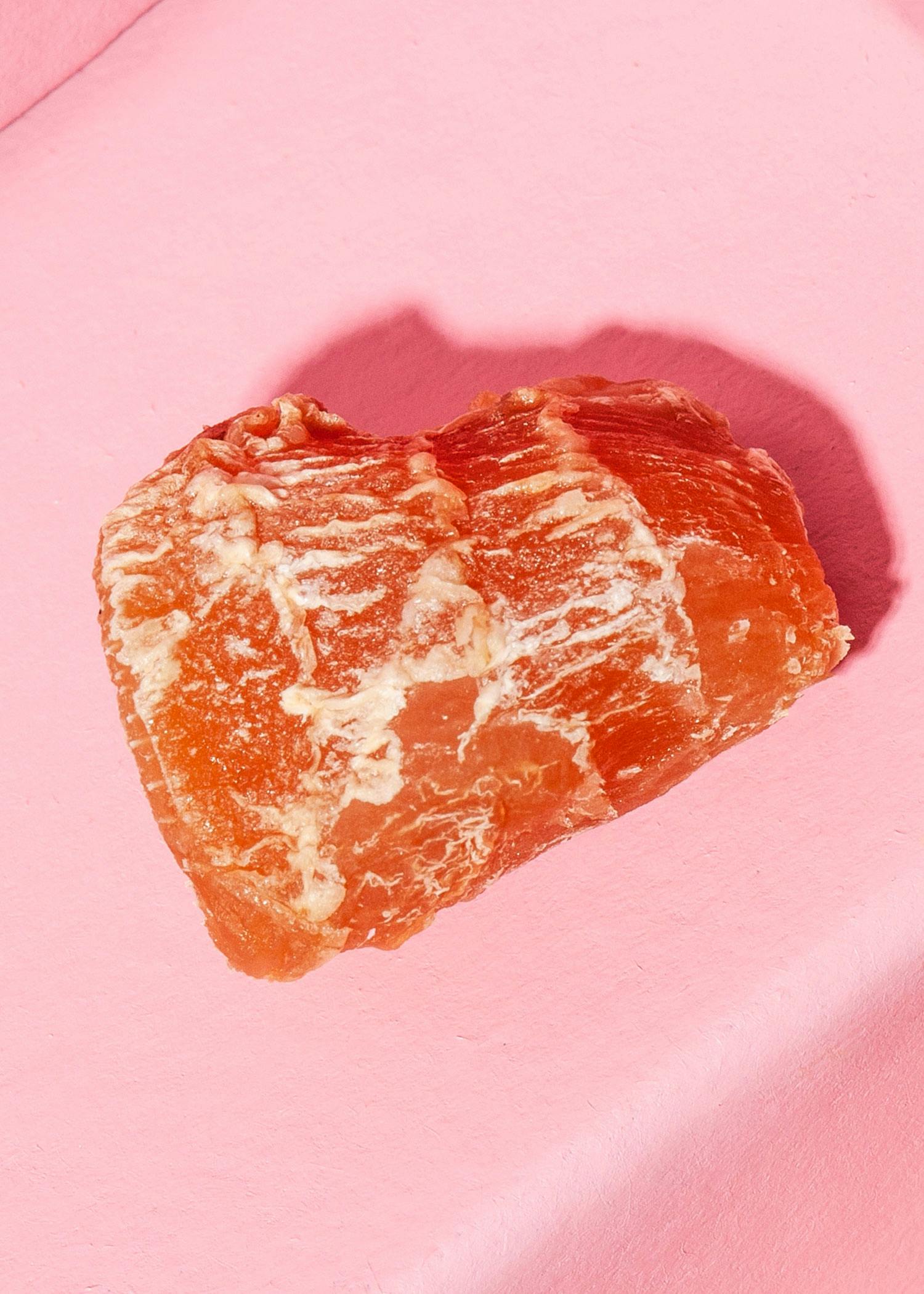 ein Stück rotes Fleisch sitzt auf einem rosa Tisch