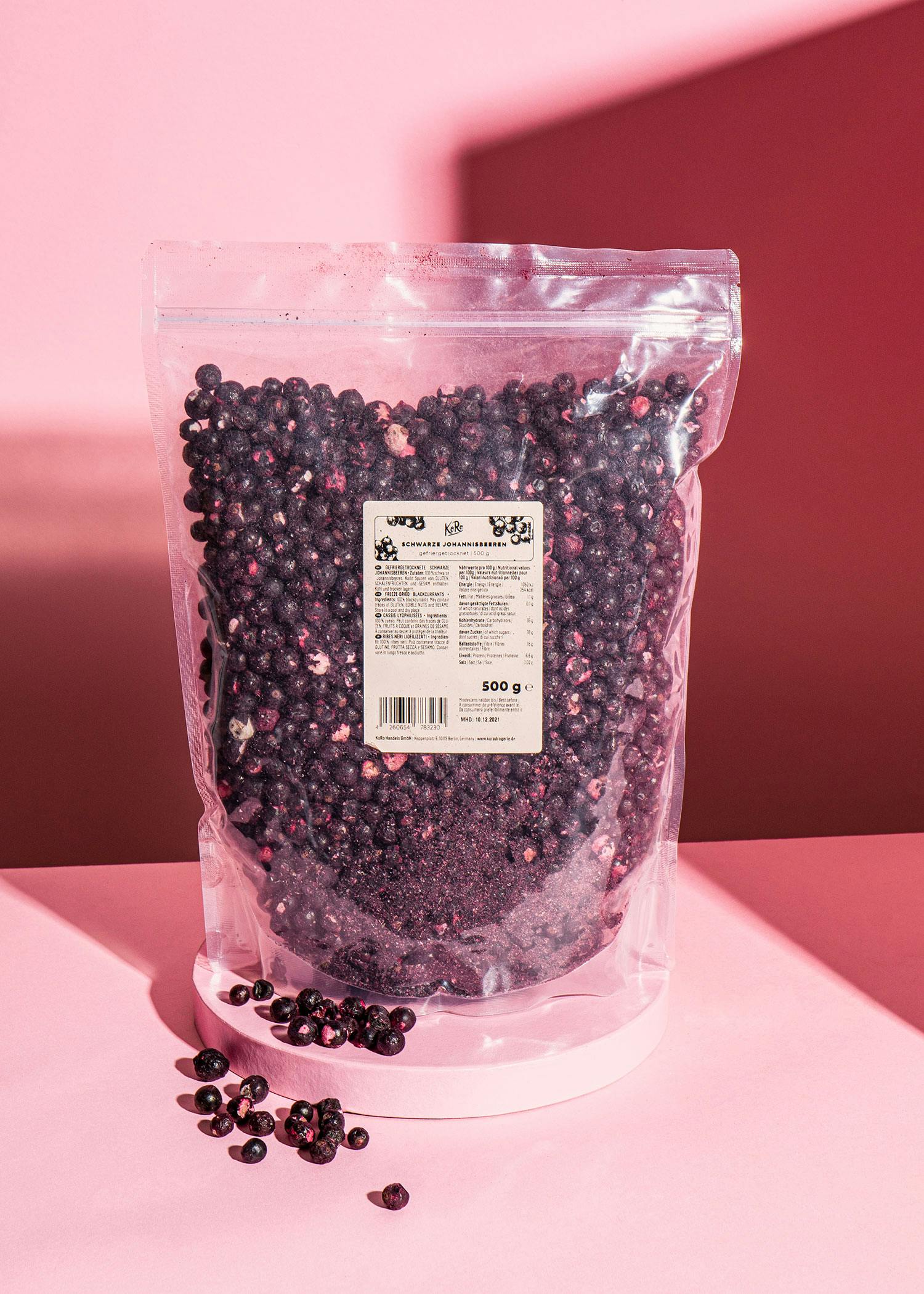 ein Plastikbeutel mit Blaubeeren steht auf einem rosa Tisch