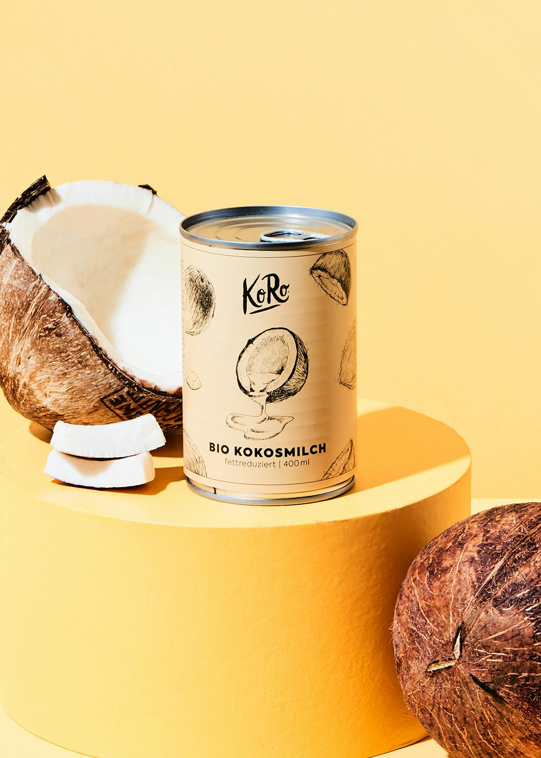 eine Dose Kokosmilch mit Kokosnüssen dahinter