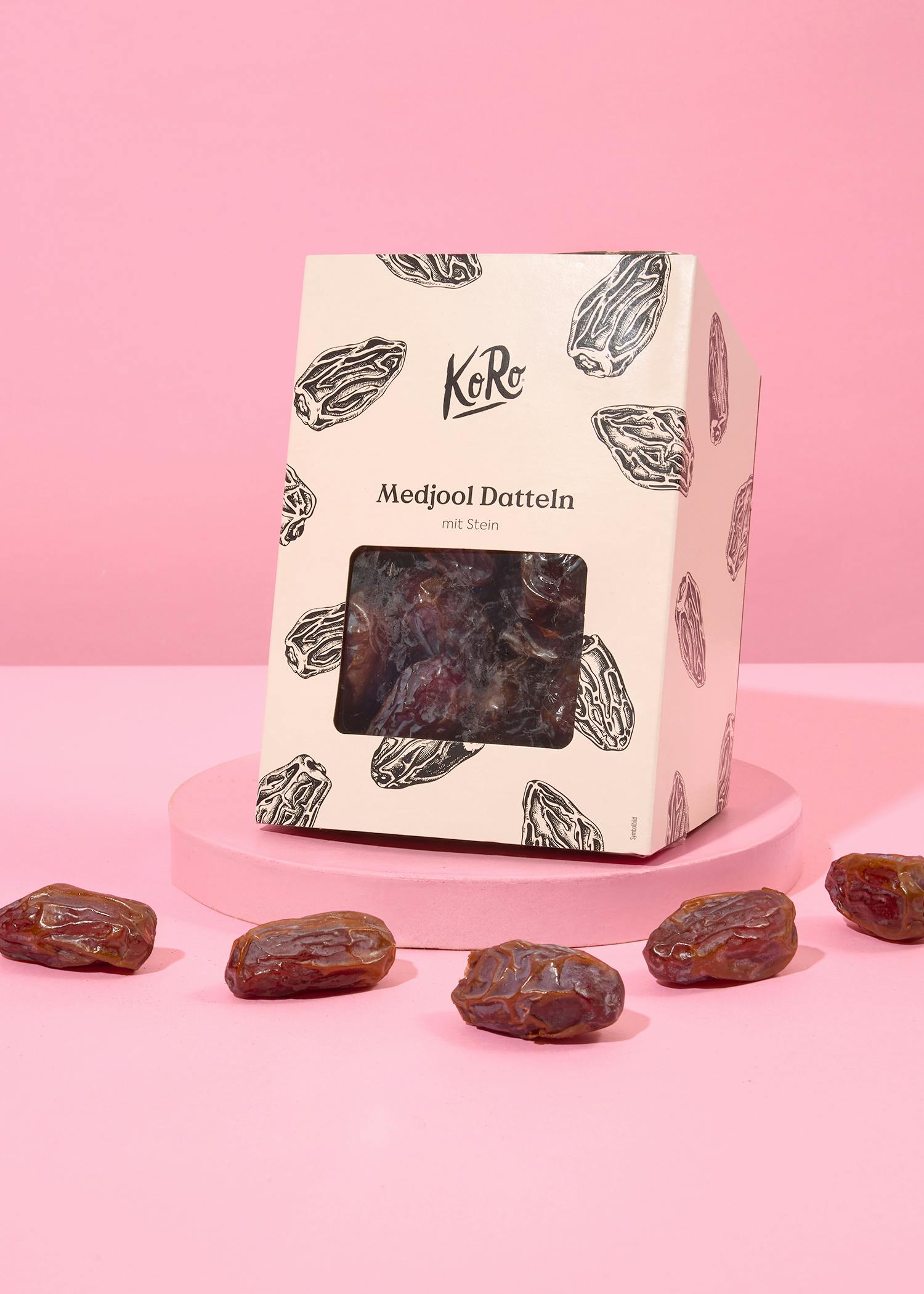 eine Schachtel mit medjool datteln steht auf einem rosa Tisch