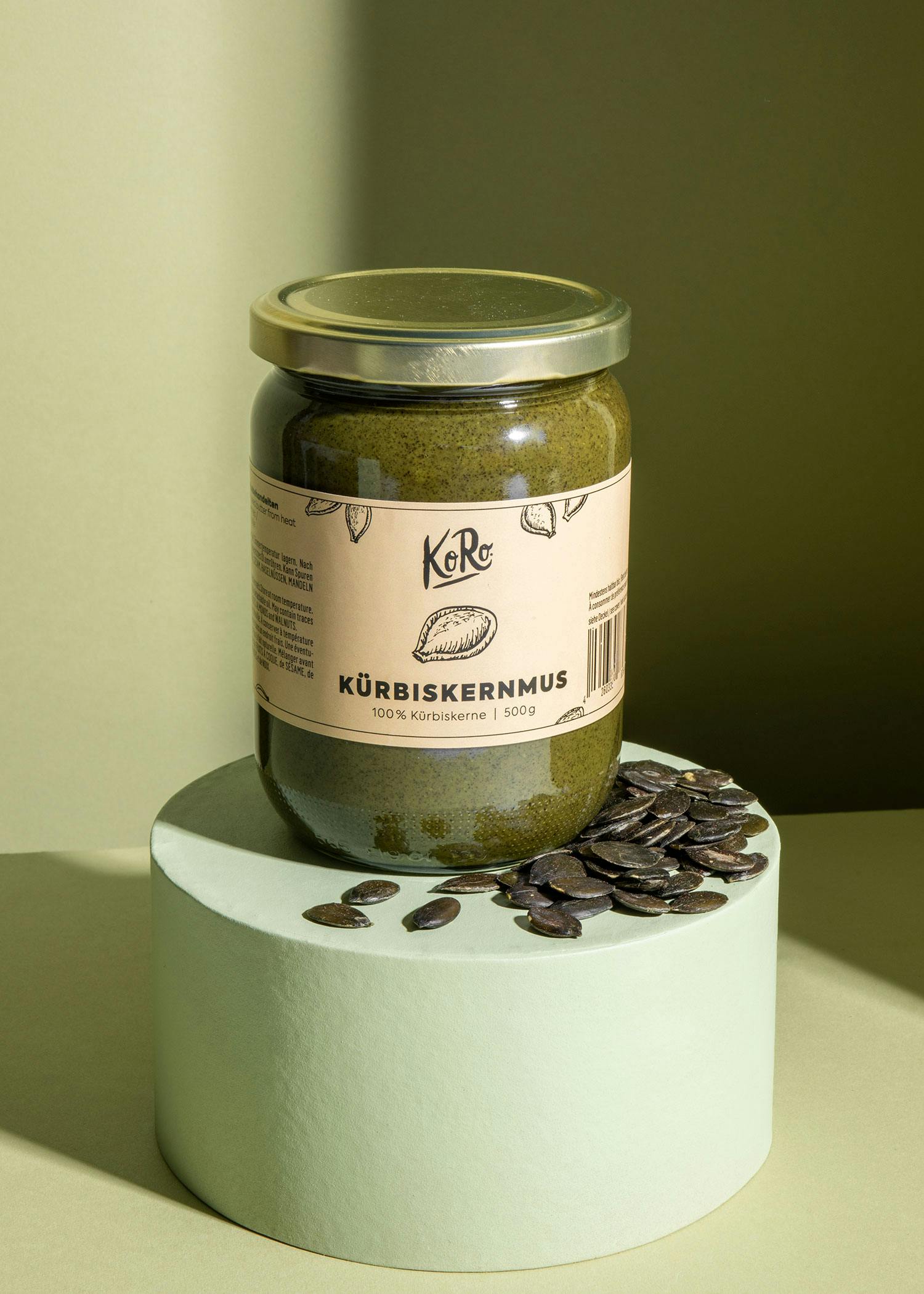 ein Glas Kürbiskernmus steht auf einem weißen Ständer