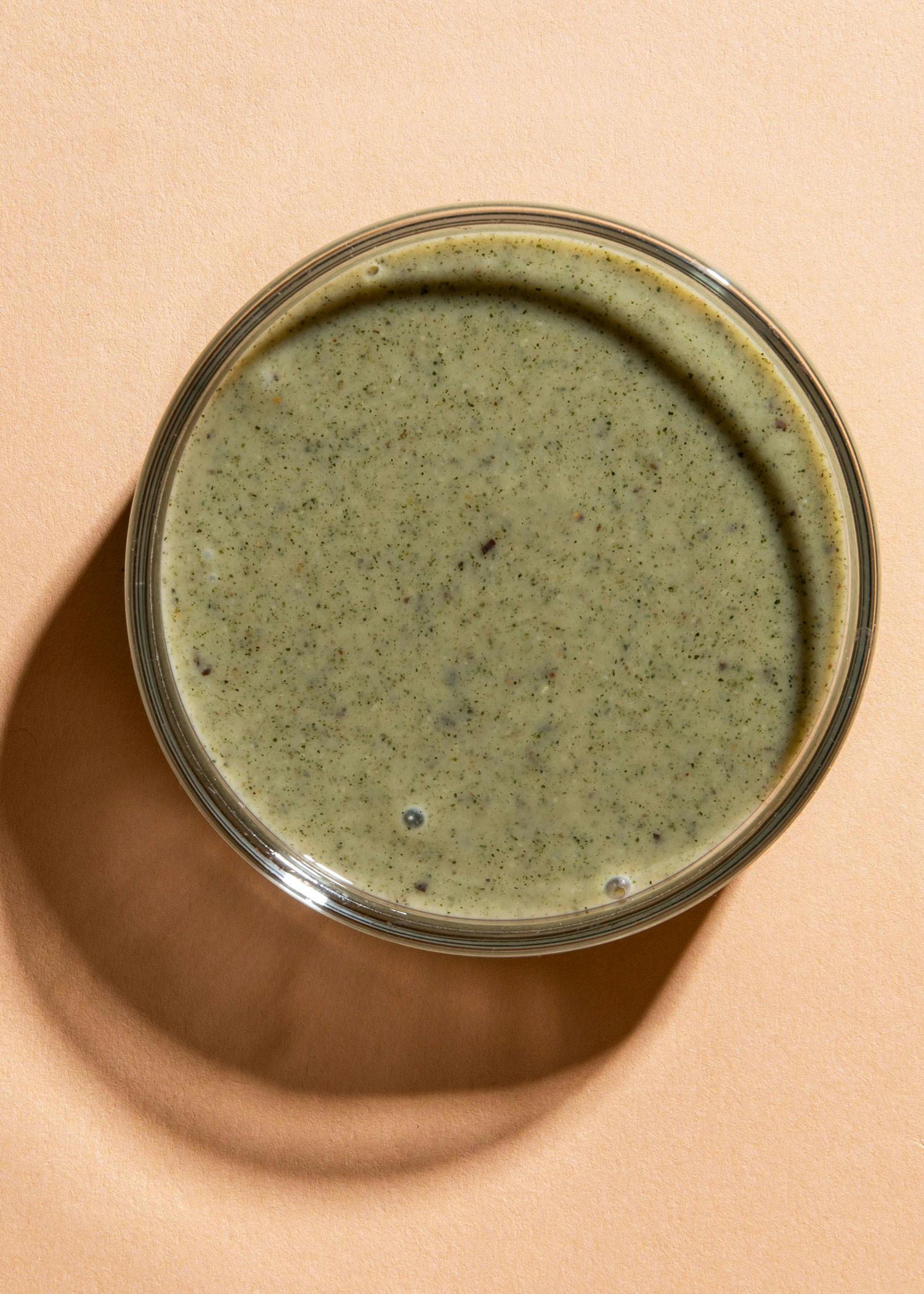 eine Glasschüssel mit grüner Soße auf einem Tisch