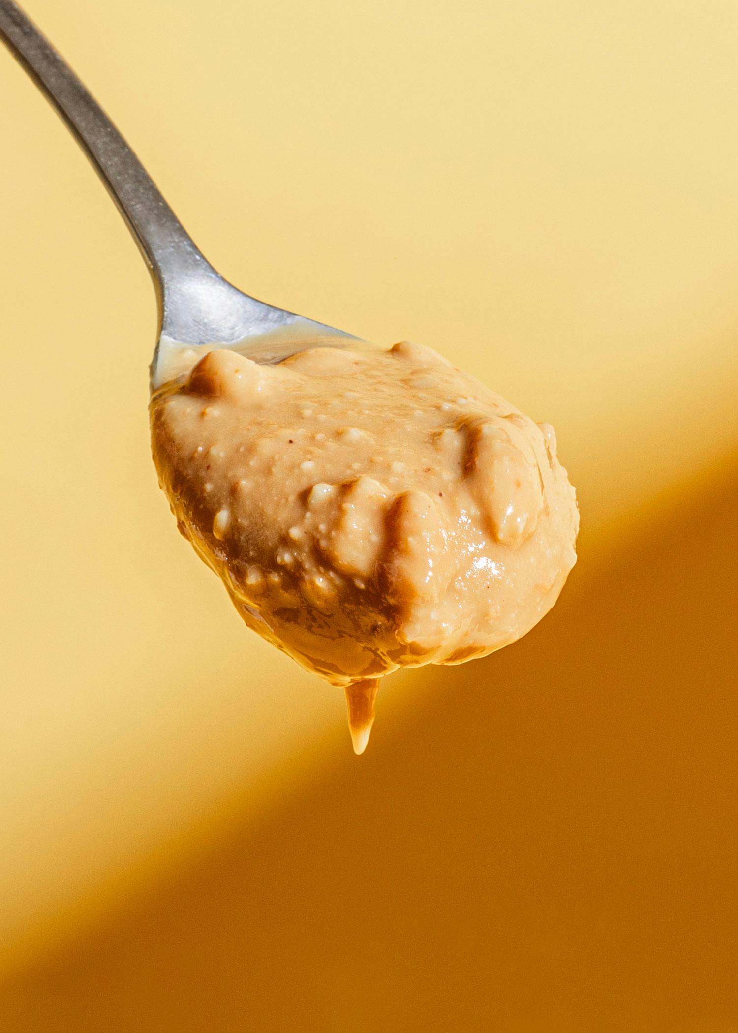 ein Löffel mit Erdnussbutter auf einem gelben Tisch