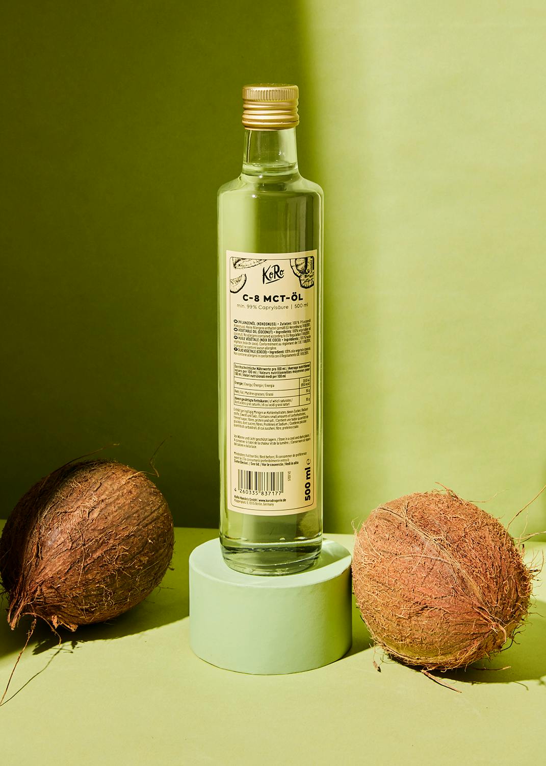 eine Flasche Kokosöl steht neben zwei Kokosnüsse