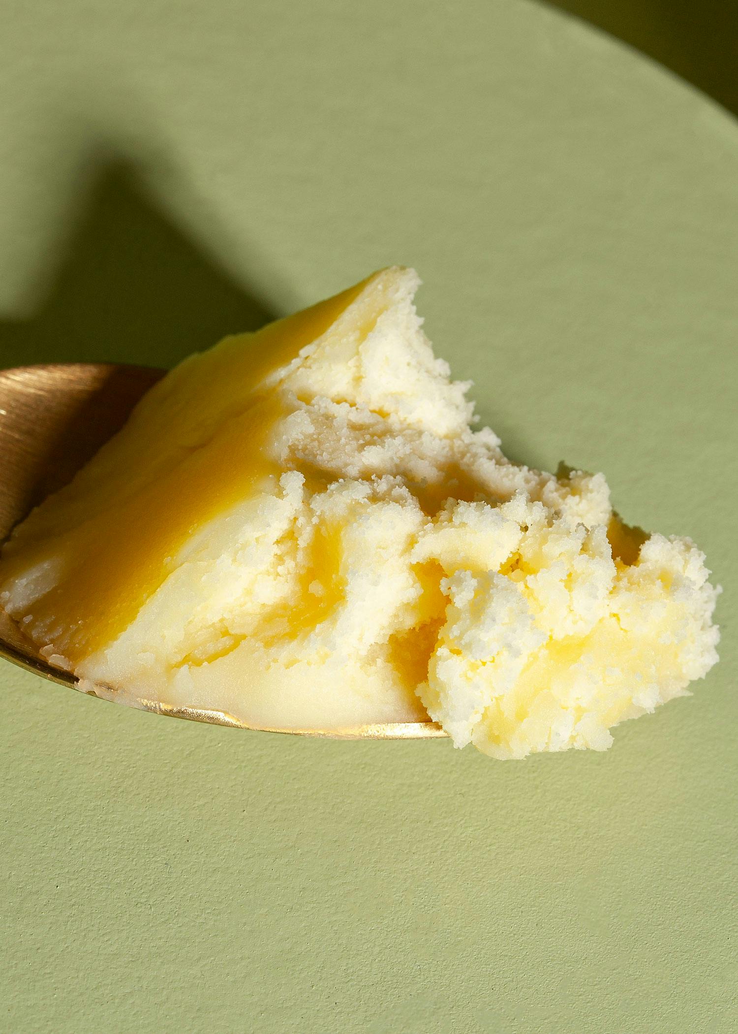 ein Löffel mit einem Stück Butter auf einem grünen Teller