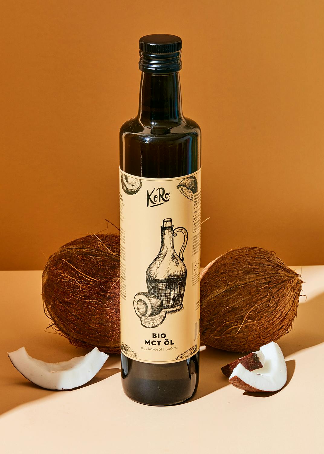eine Flasche Bio-Mct-Öl neben Kokosnüssen