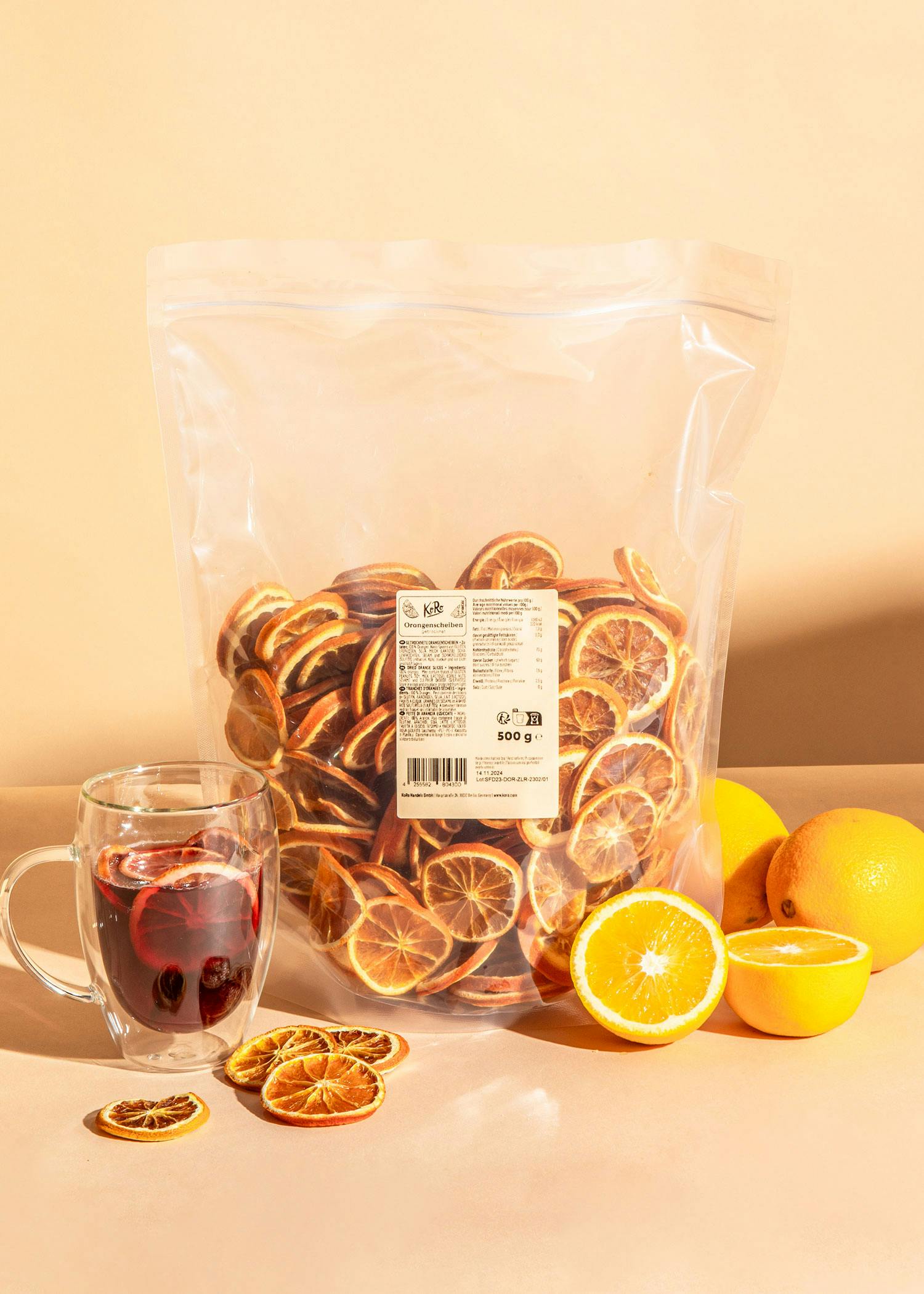 eine Tüte getrockneter Orangenscheiben steht neben einer Tasse glühwein