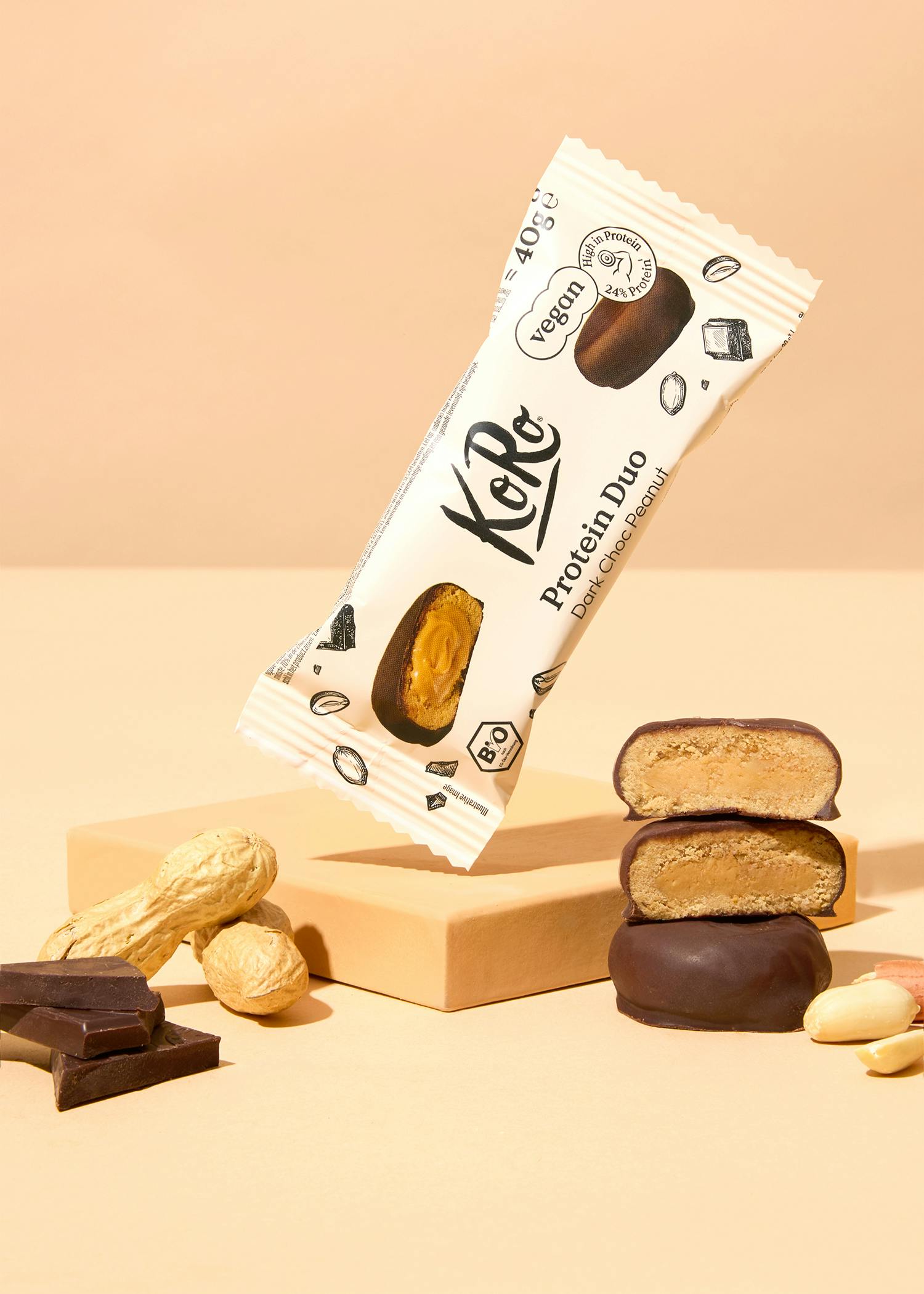 eine verpackte protein-duo-bar liegt auf einem tisch neben erdnüssen und schokolade