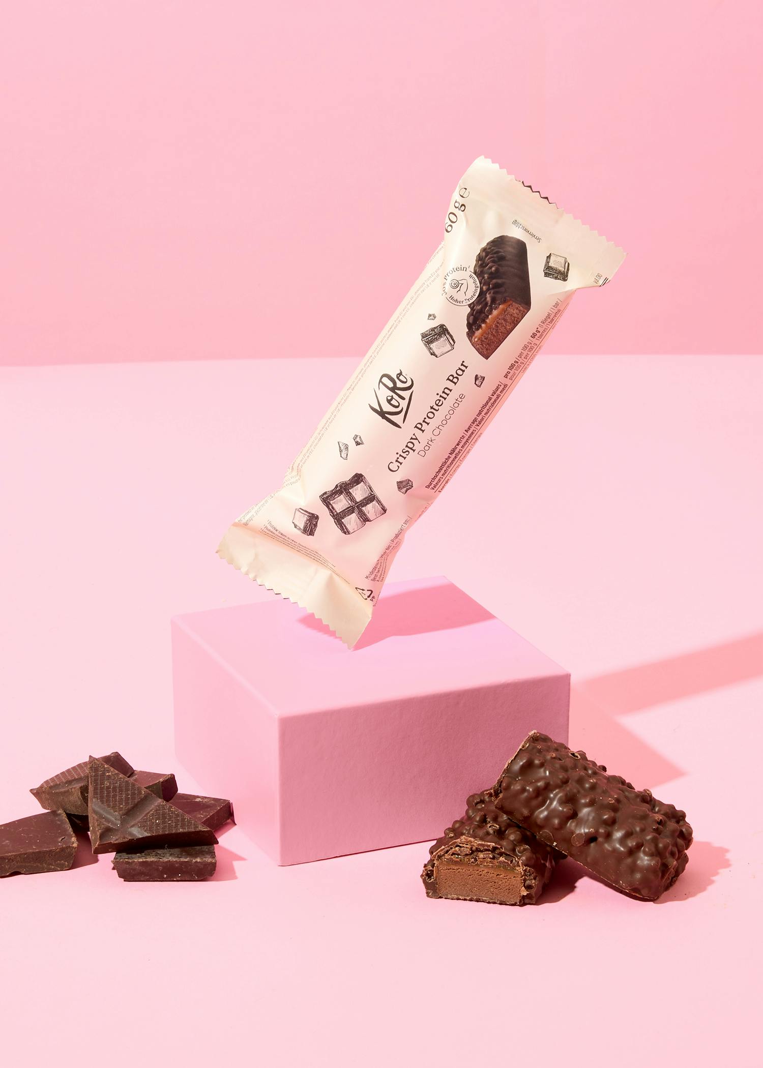 eine Karamell-Schokoladenprotein-Bar liegt auf einem rosa Sockel