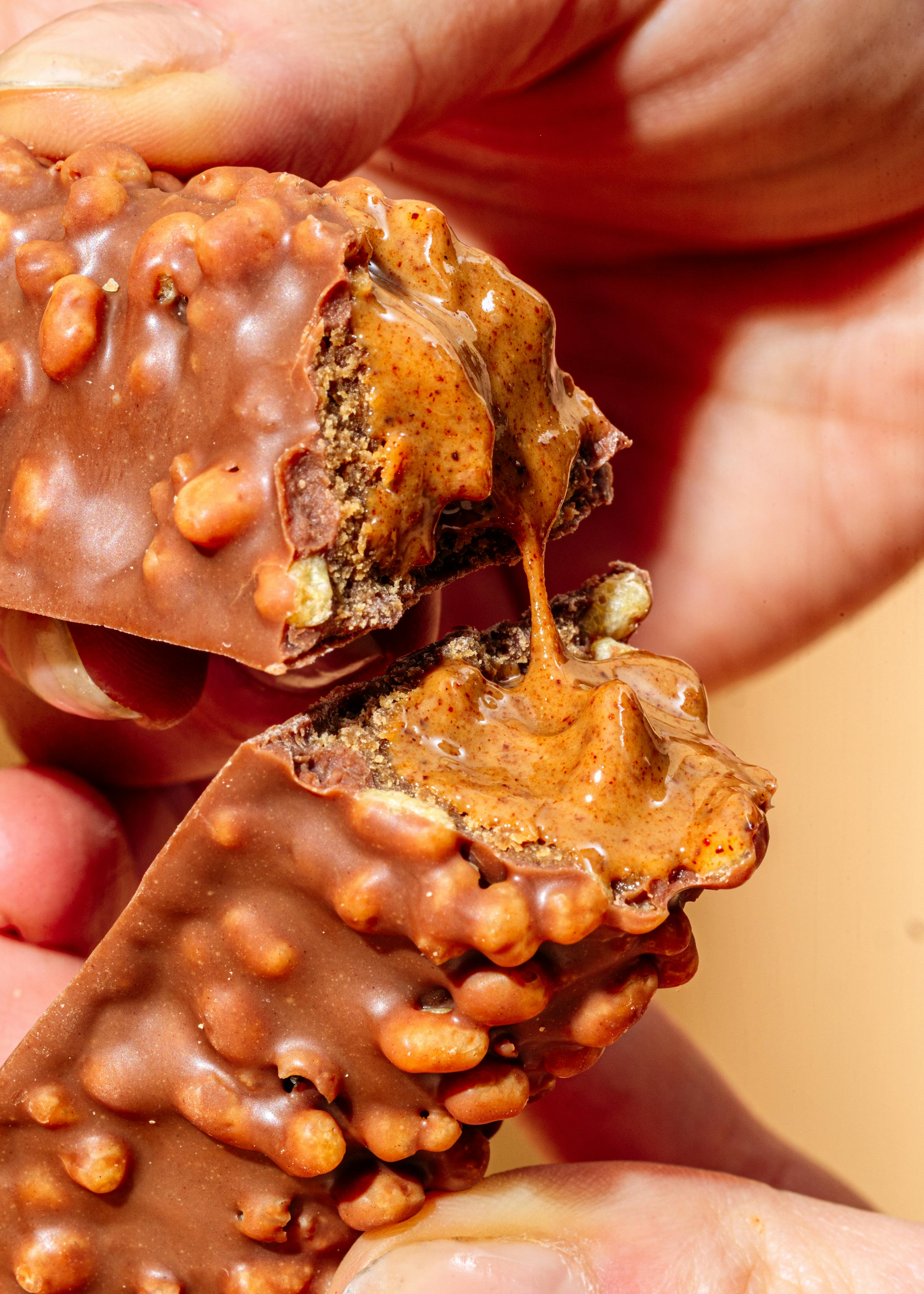 eine Person isst eine Schokoladenstange mit Erdnussbutter darauf