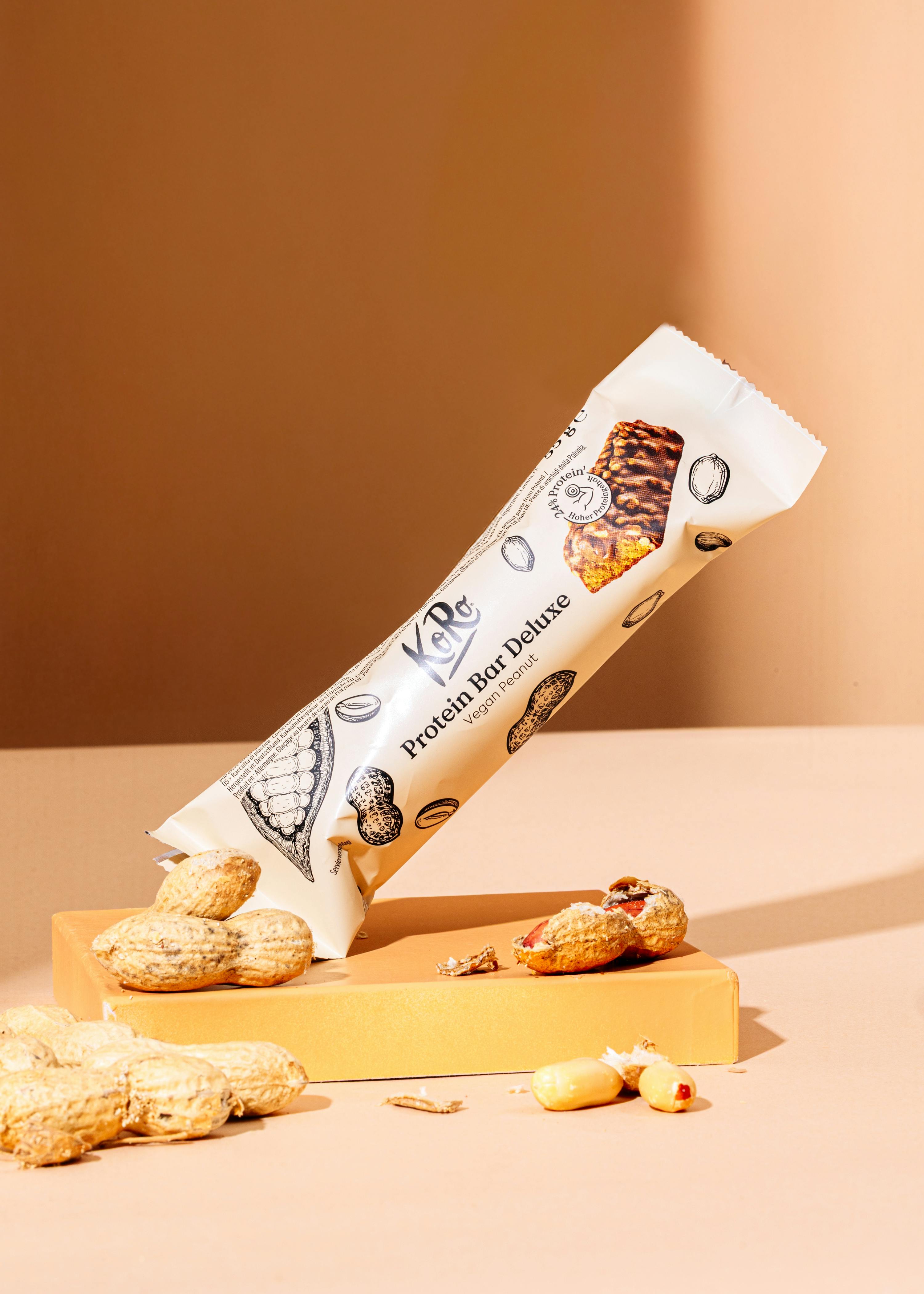 eine weiße protein-bar deluxe liegt auf einem tisch neben erdnüssen