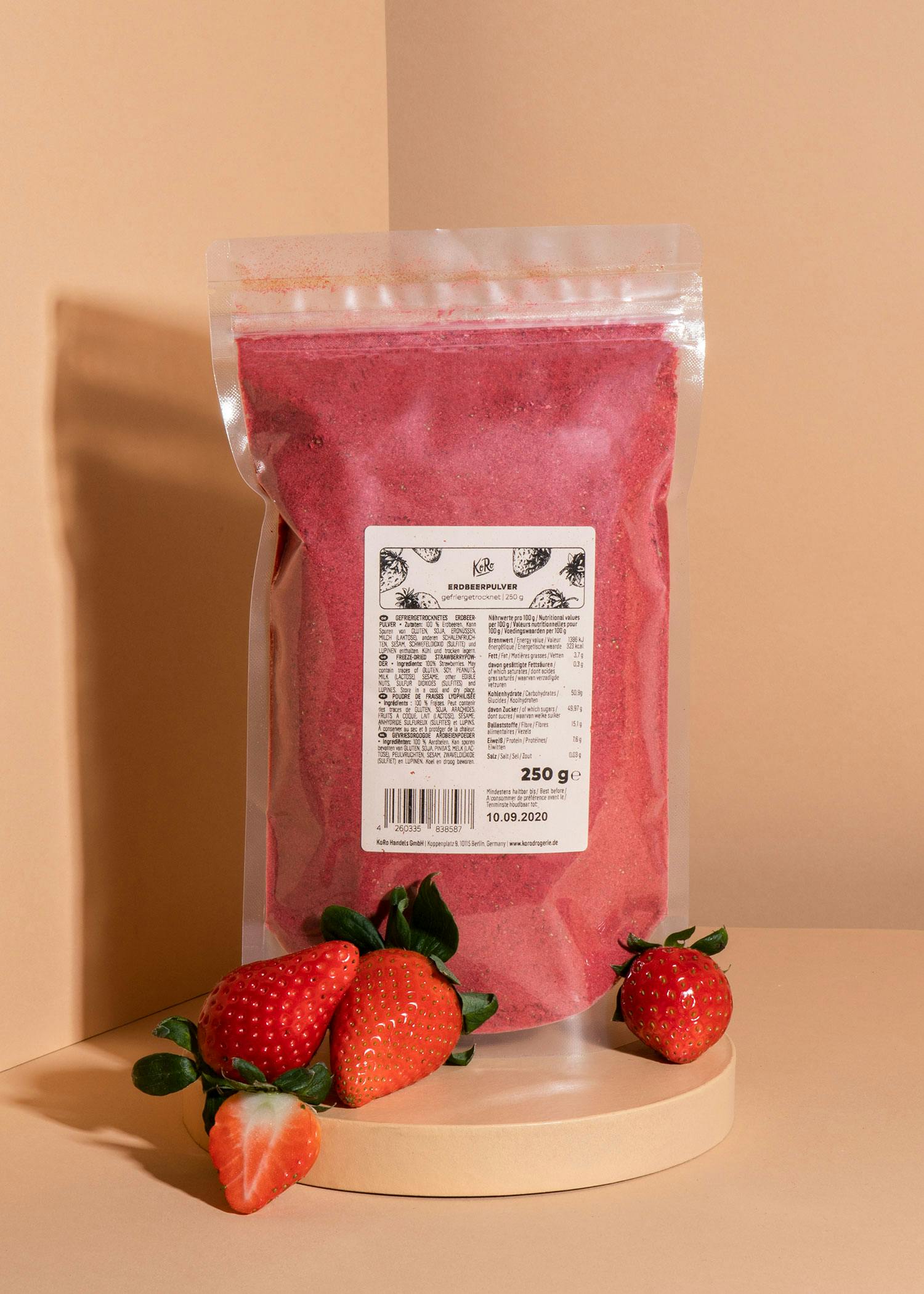 eine Tüte Erdbeerpulver steht auf einem Tisch neben Erdbeeren