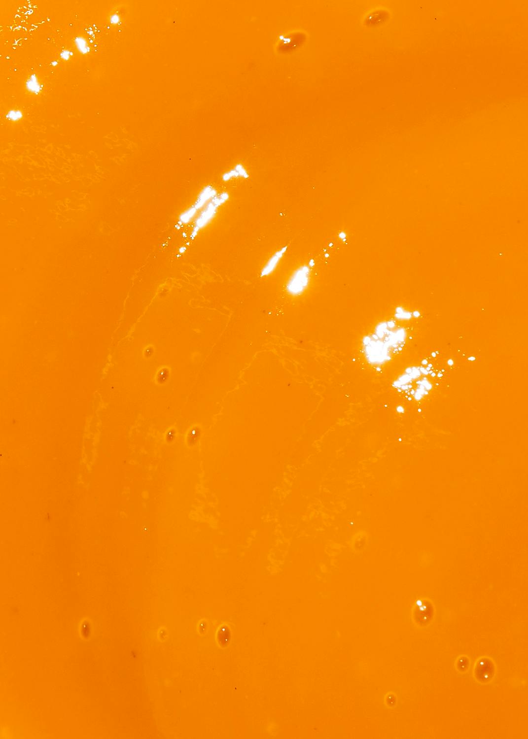 eine Nahaufnahme einer orangefarbenen Flüssigkeit mit weißen Blasen
