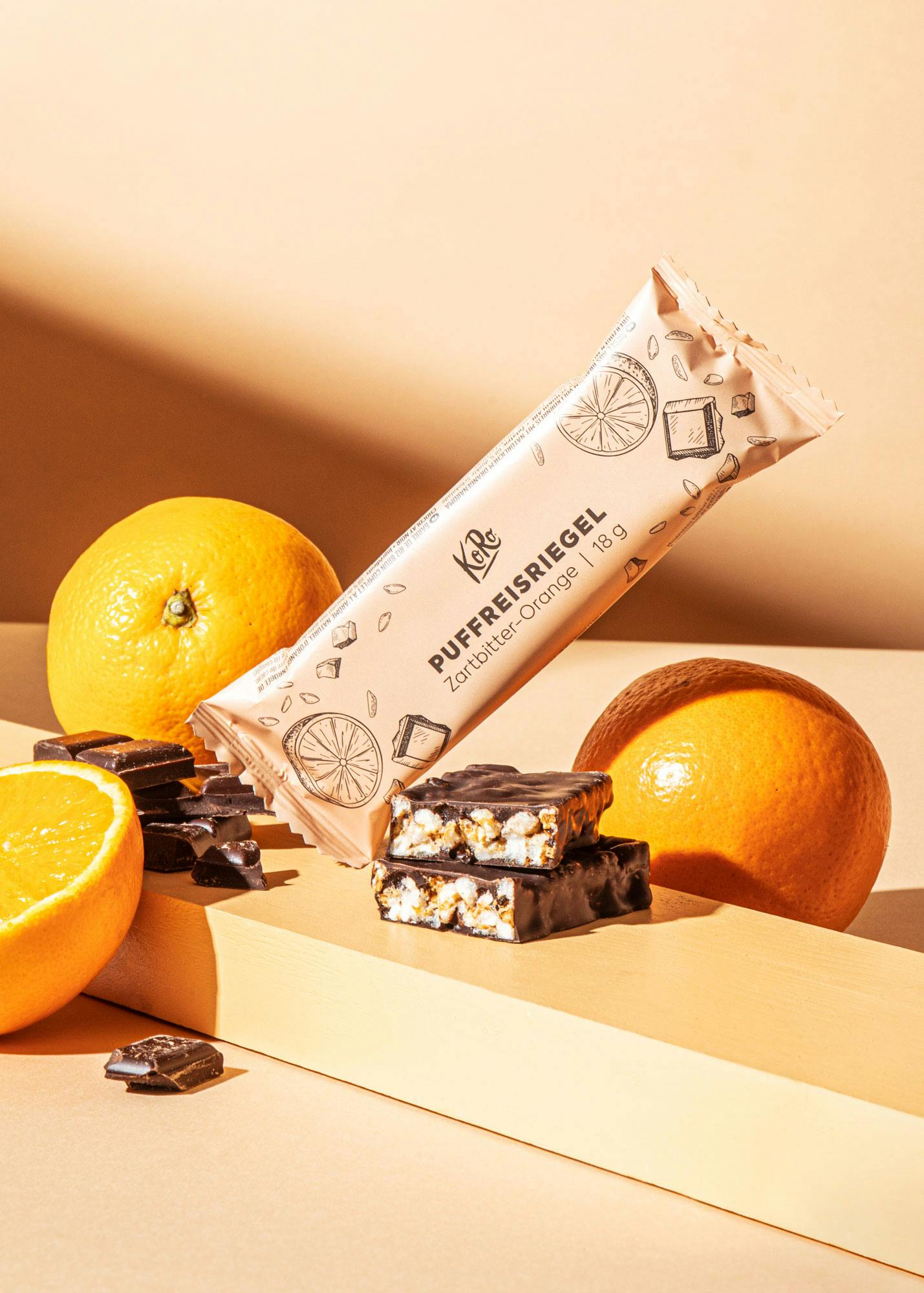 ein puffreisriegel liegt neben orangen und schokolade