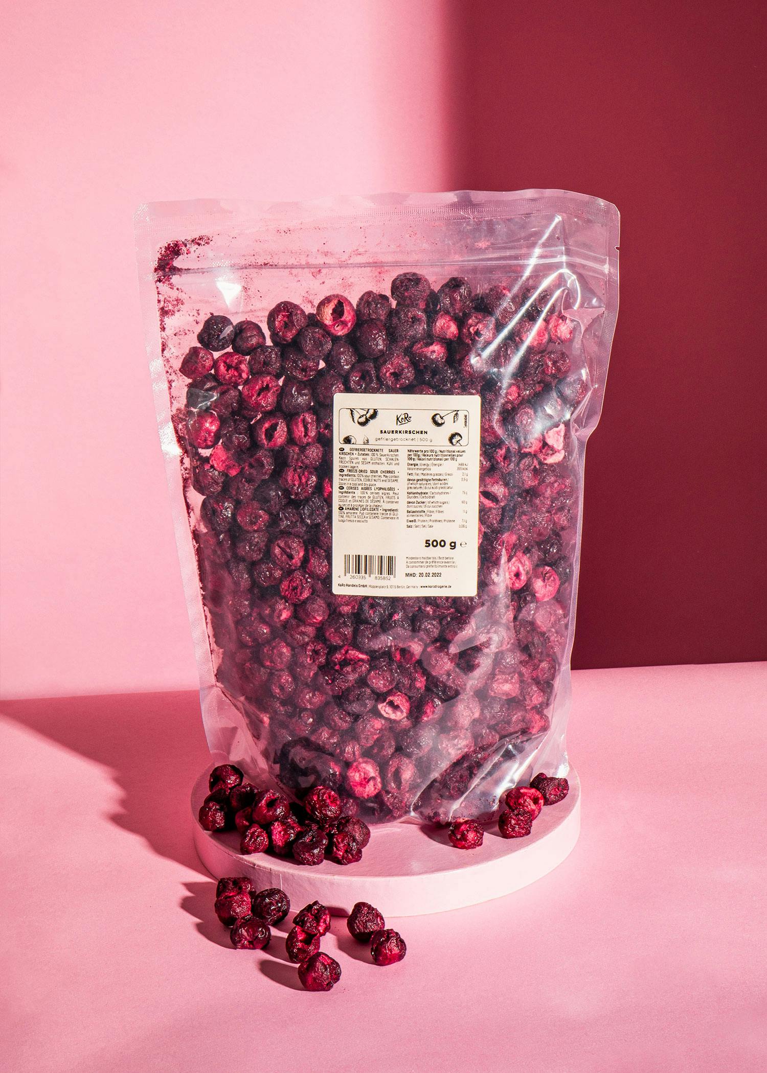 ein Plastikbeutel mit getrockneten Blaubeeren steht auf einem rosa Tisch