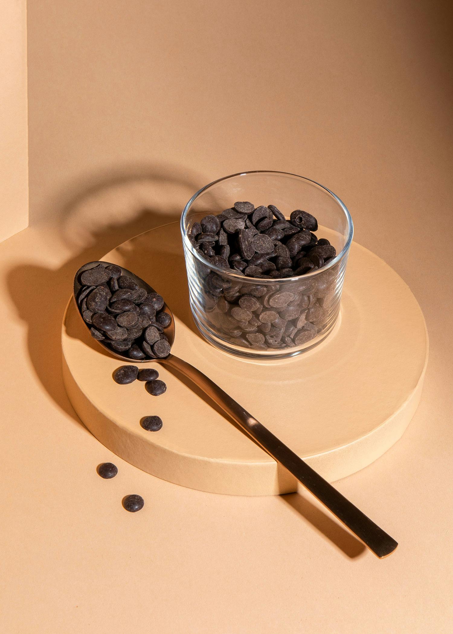 eine Schüssel Schokoladenchips neben einem Löffel Schokoladenchips