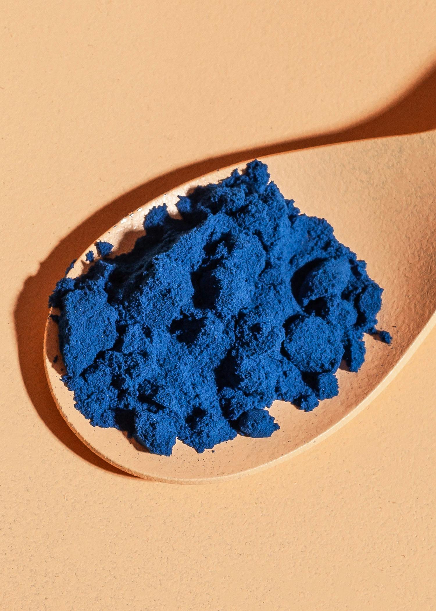 ein Holzlöffel mit einem Haufen blauer Flüssigkeit darin