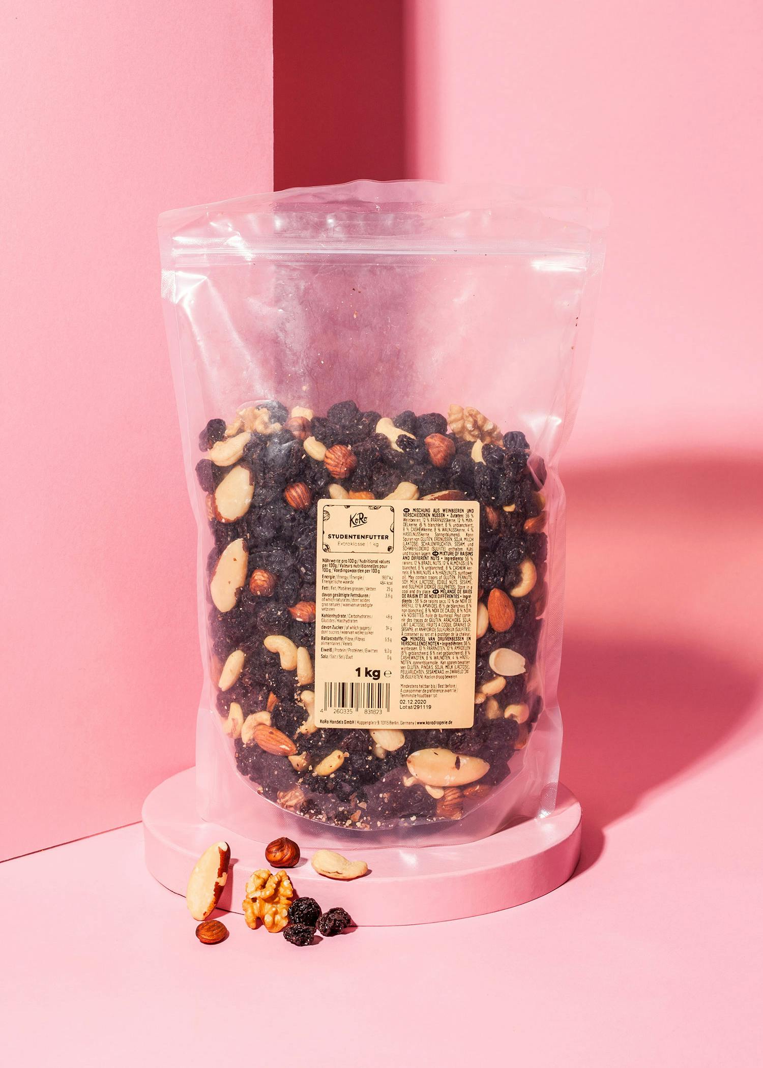 eine Plastiktüte mit Nüssen und Rosinen steht auf einem rosa Ständer